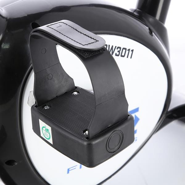 Czarne pedal ruszajacego roweru z regulowanym paskiem na bialo-czarnym urzadzeniu fitness.