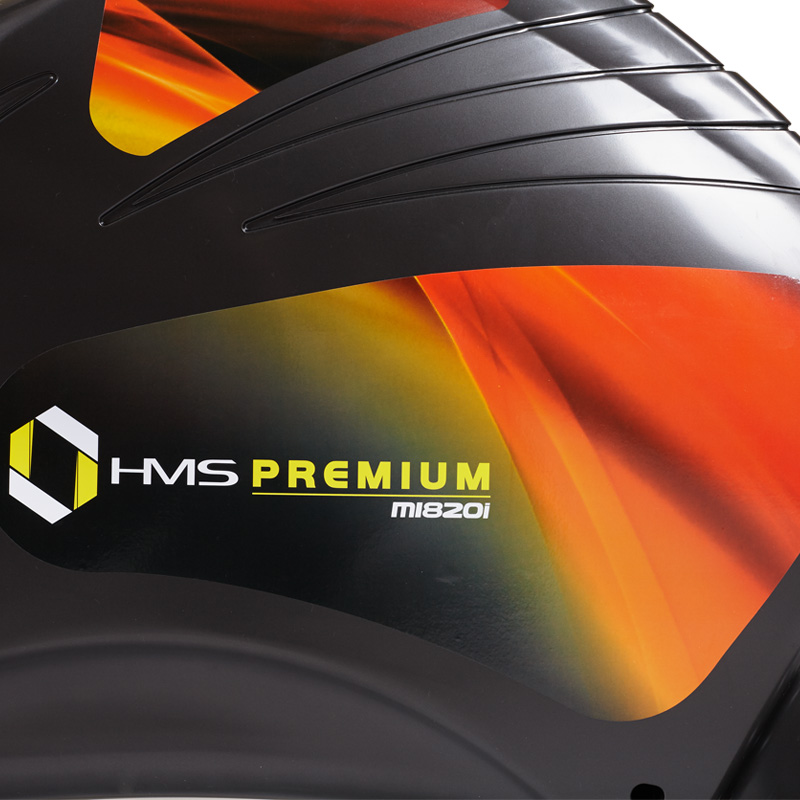 Zbliżenie czarnego urządzenia fitness z pomarańczowymi akcentami, logo i napisem HMS PREMIUM M1820i.
