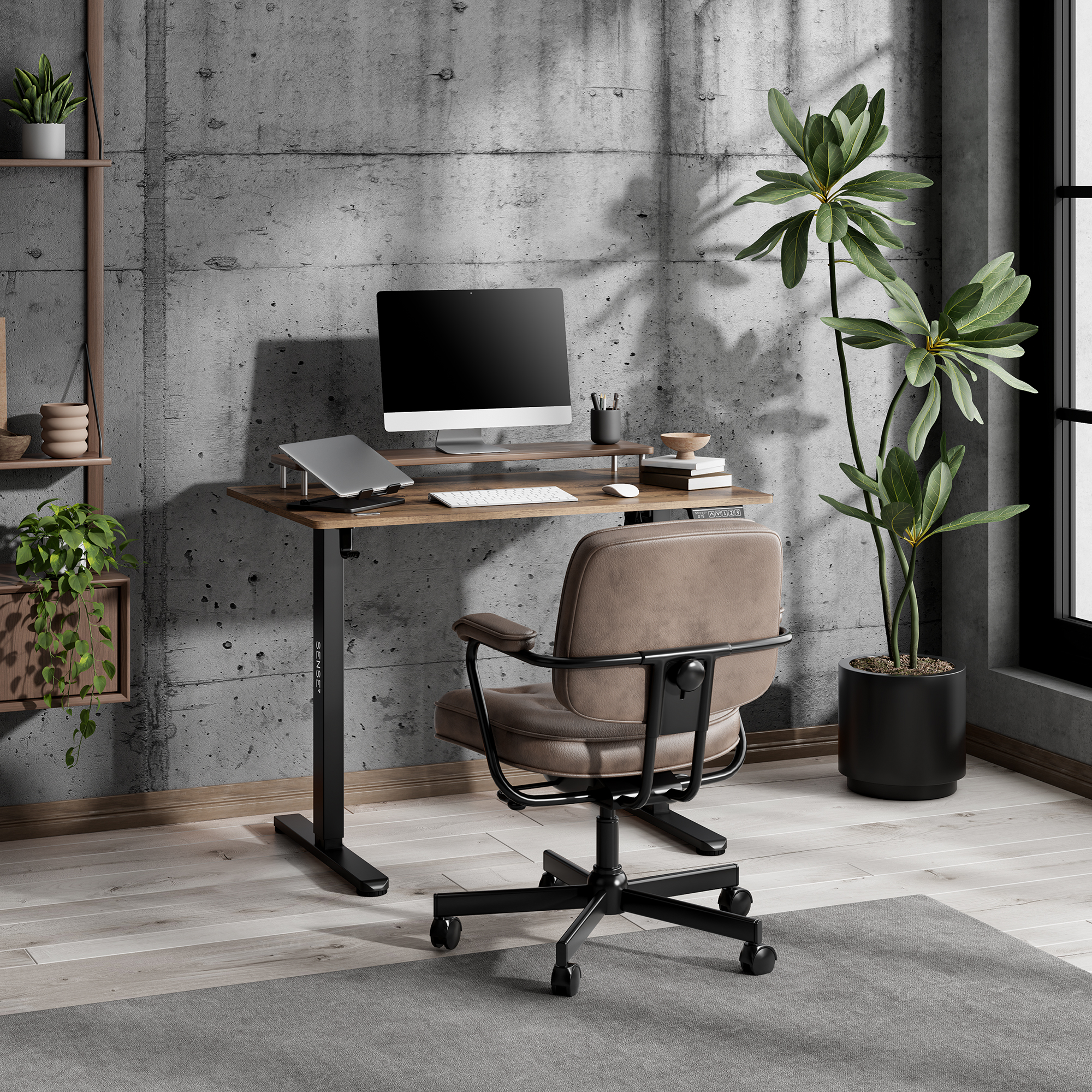 Moderna zona de trabajo con escritorio, monitor, silla y plantas frente a una pared de hormigón.