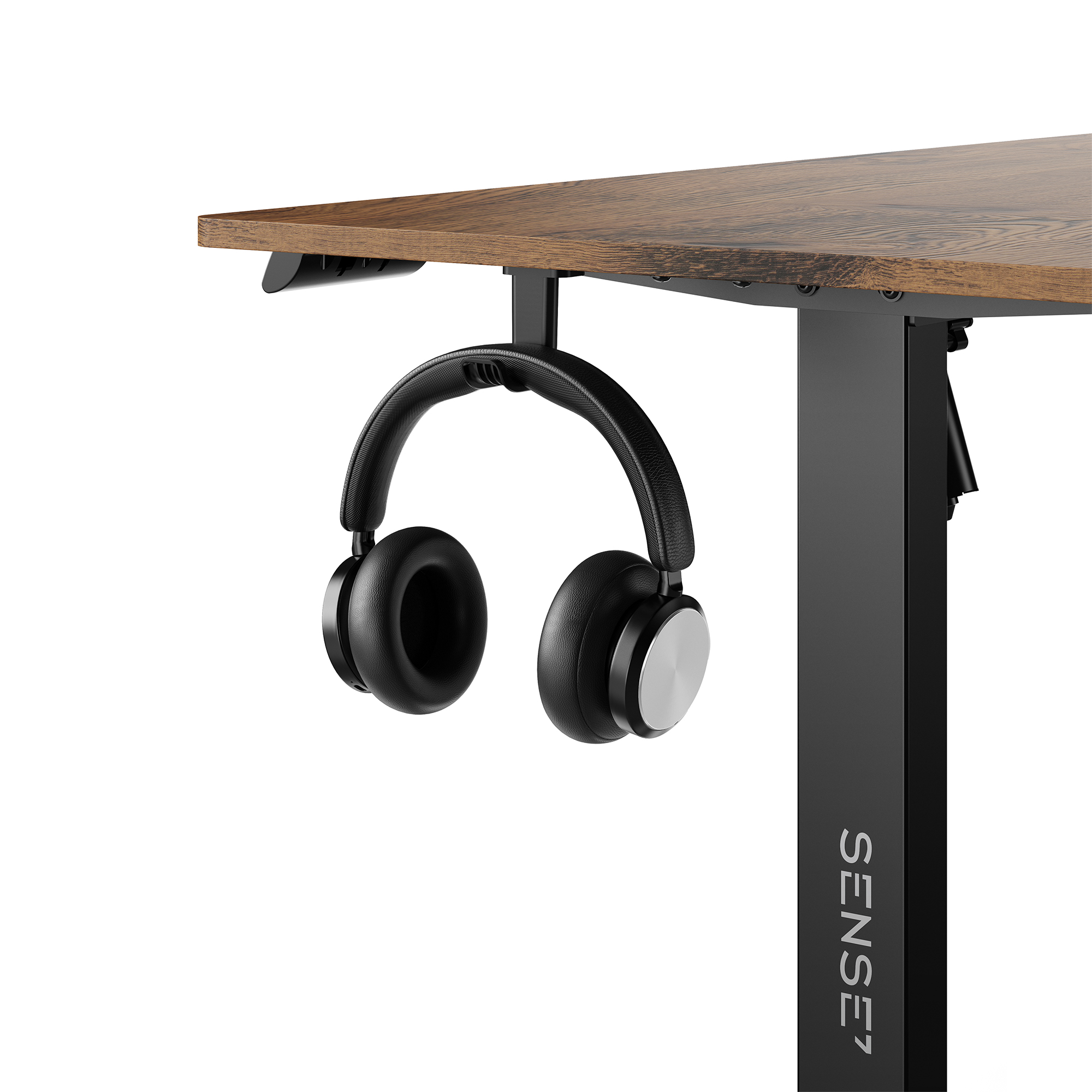Auriculares supraaurales negros cuelgan de un soporte bajo un escritorio de madera con pata negra.