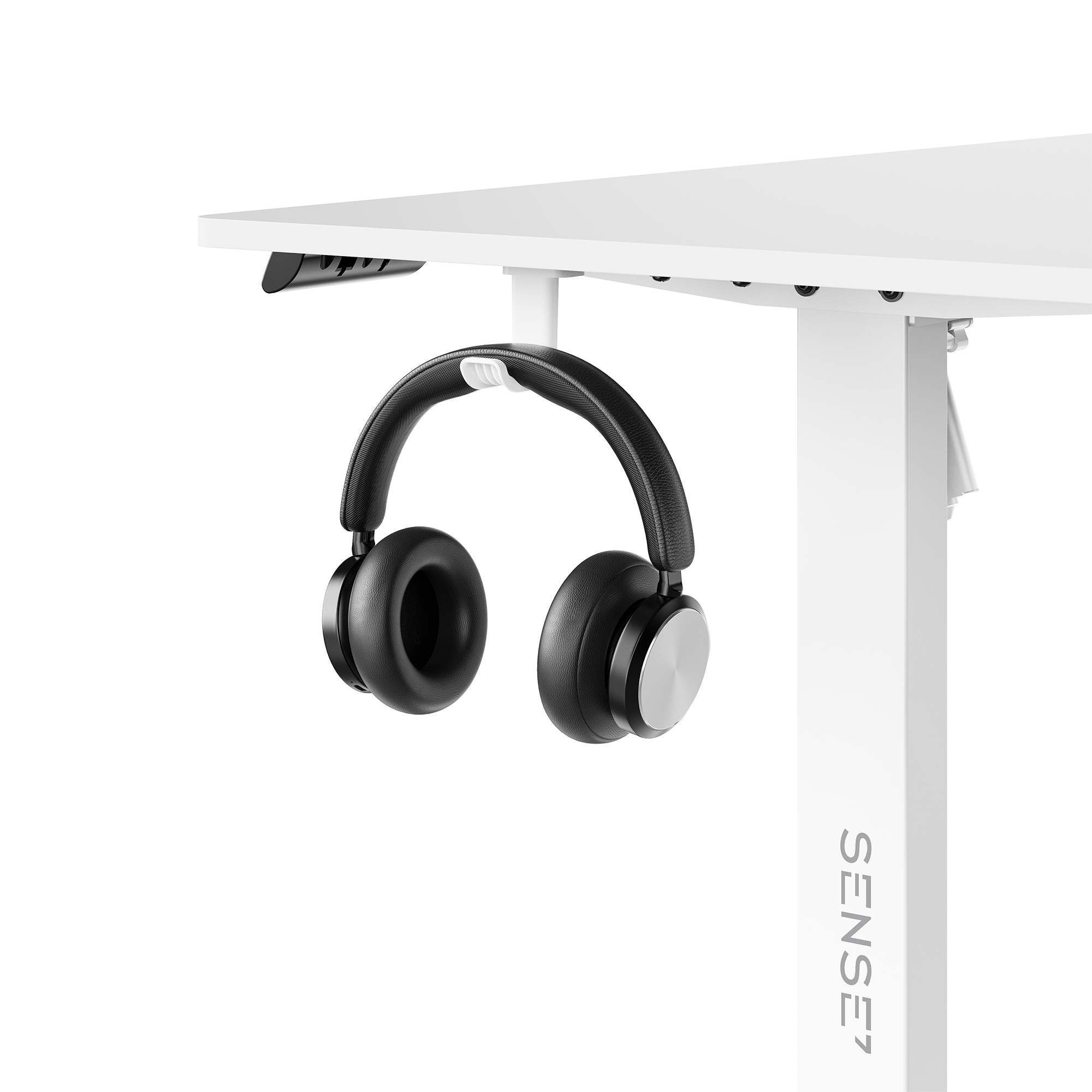 Auriculares negros cuelgan de un soporte blanco bajo un escritorio blanco.
