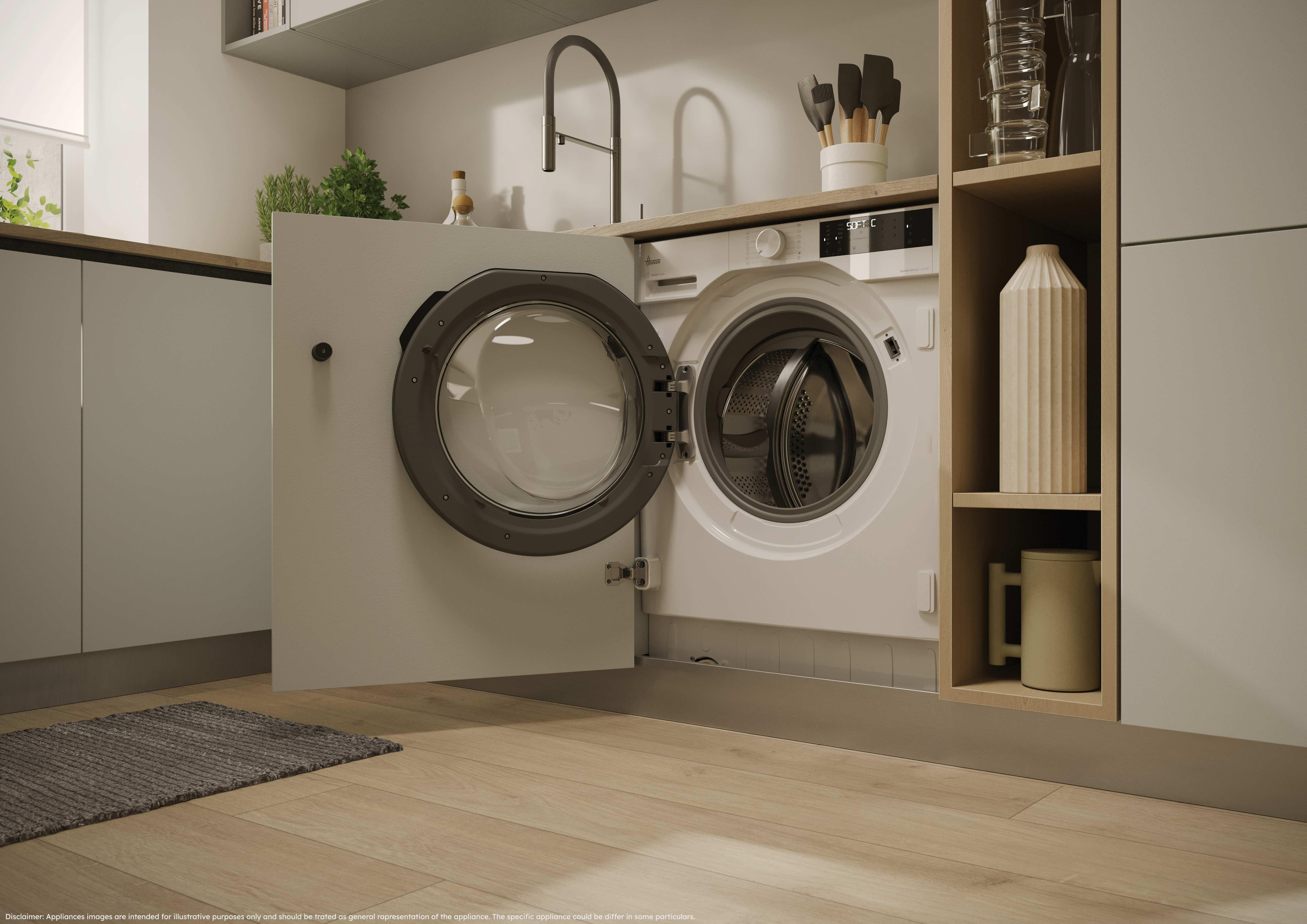 Una lavatrice bianca con lo sportello aperto è installata in una cucina moderna con pavimenti in legno e mobili chiari.