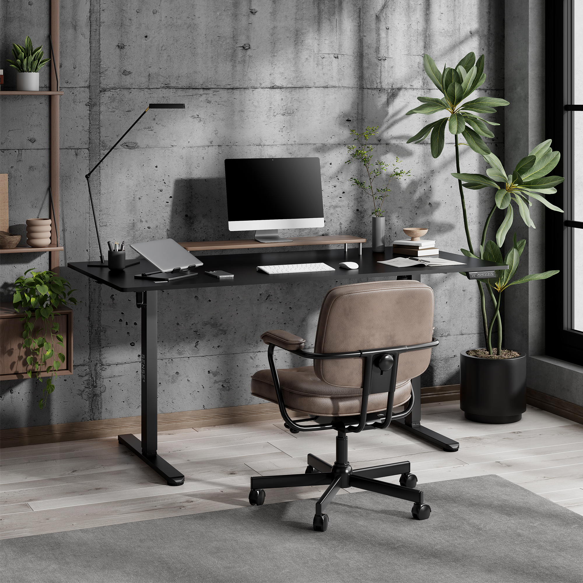 Configuración de escritorio moderna con ordenador, lámpara, silla y plantas contra una pared de hormigón.