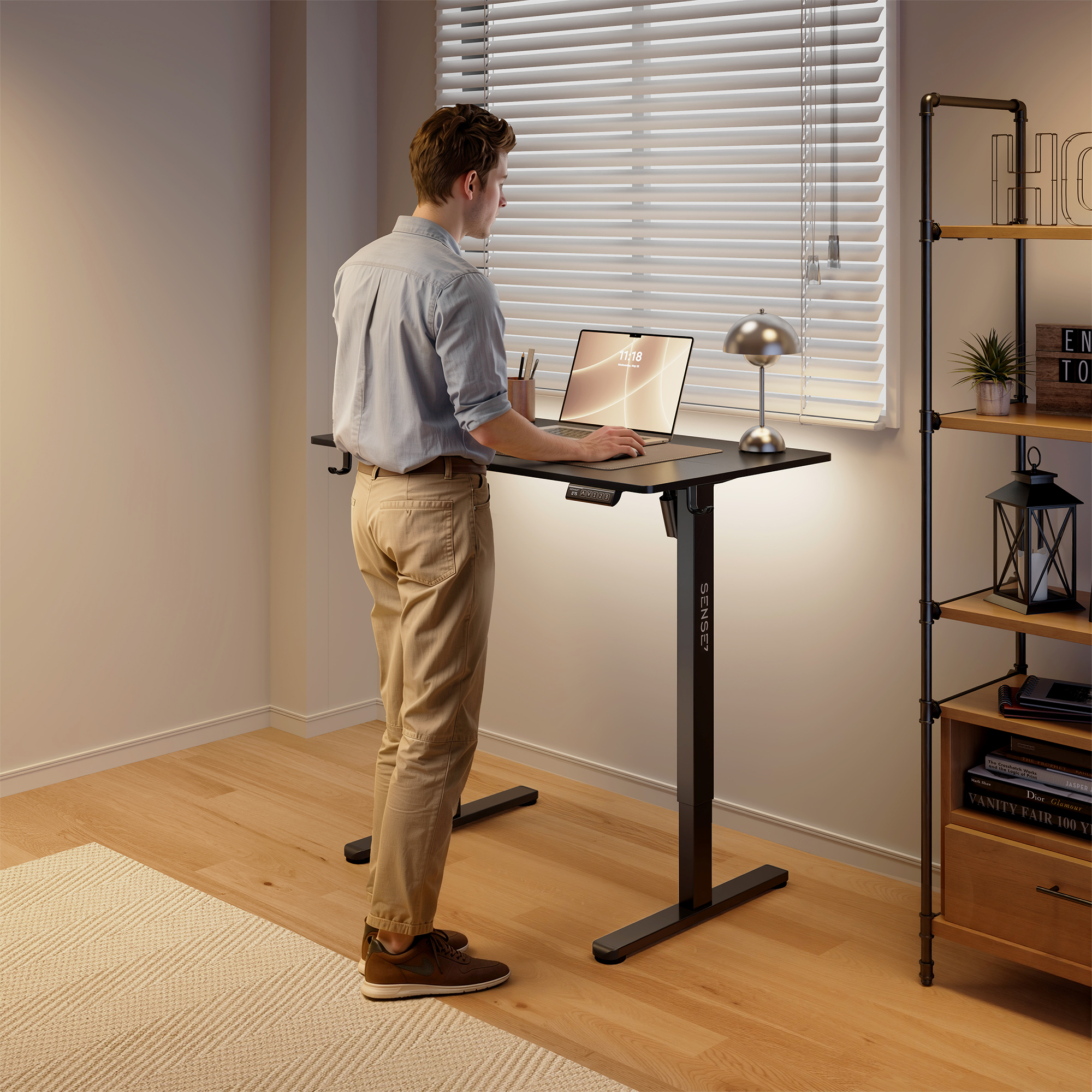 Un hombre está de pie en un escritorio ajustable en una habitación luminosa, trabajando en una computadora.