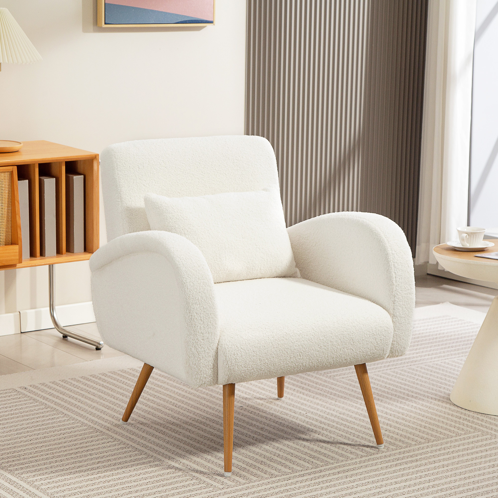 Un sillón de felpa blanco con cojín sobre una alfombra clara en una habitación con mueble de madera y mesita.