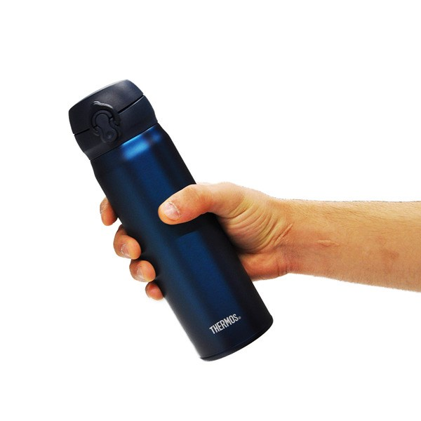 Bir el, beyaz arka planda koyu mavi bir Thermos seyahat kupası tutuyor.