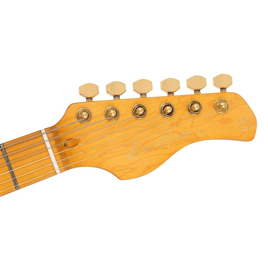 Ön tarafında altı altın akort burgusu ve imza bulunan açık renk ahşap gitar başlığının yakın çekimi.