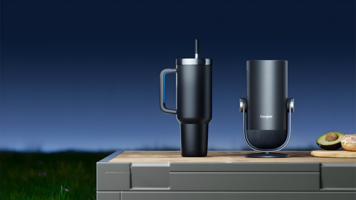 Un gobelet noir et un appareil électronique noir posés sur une table extérieure la nuit.