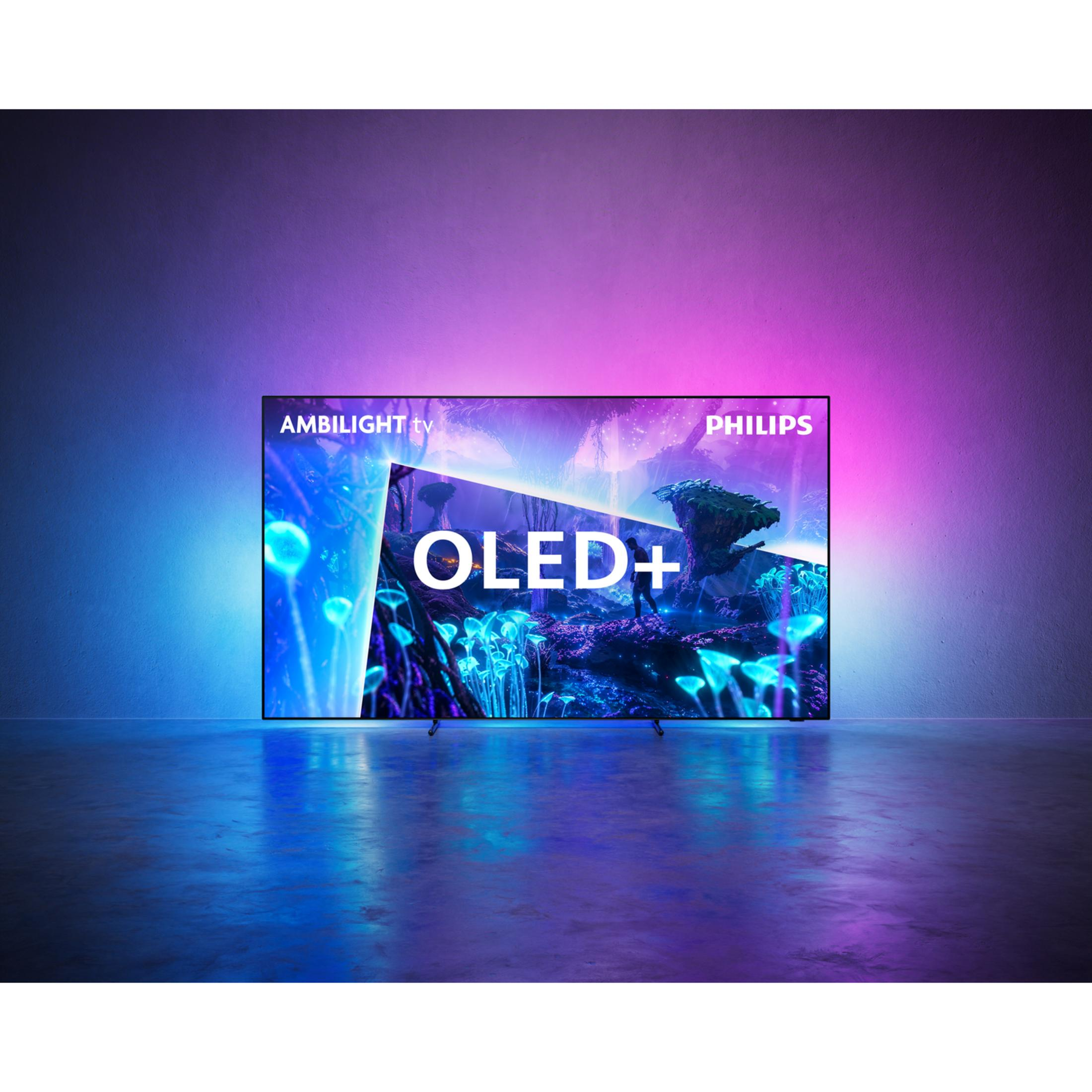 Telewizor Philips Ambilight OLED+ przy ścianie z niebieskim i różowym światłem otoczenia w pustym pokoju.