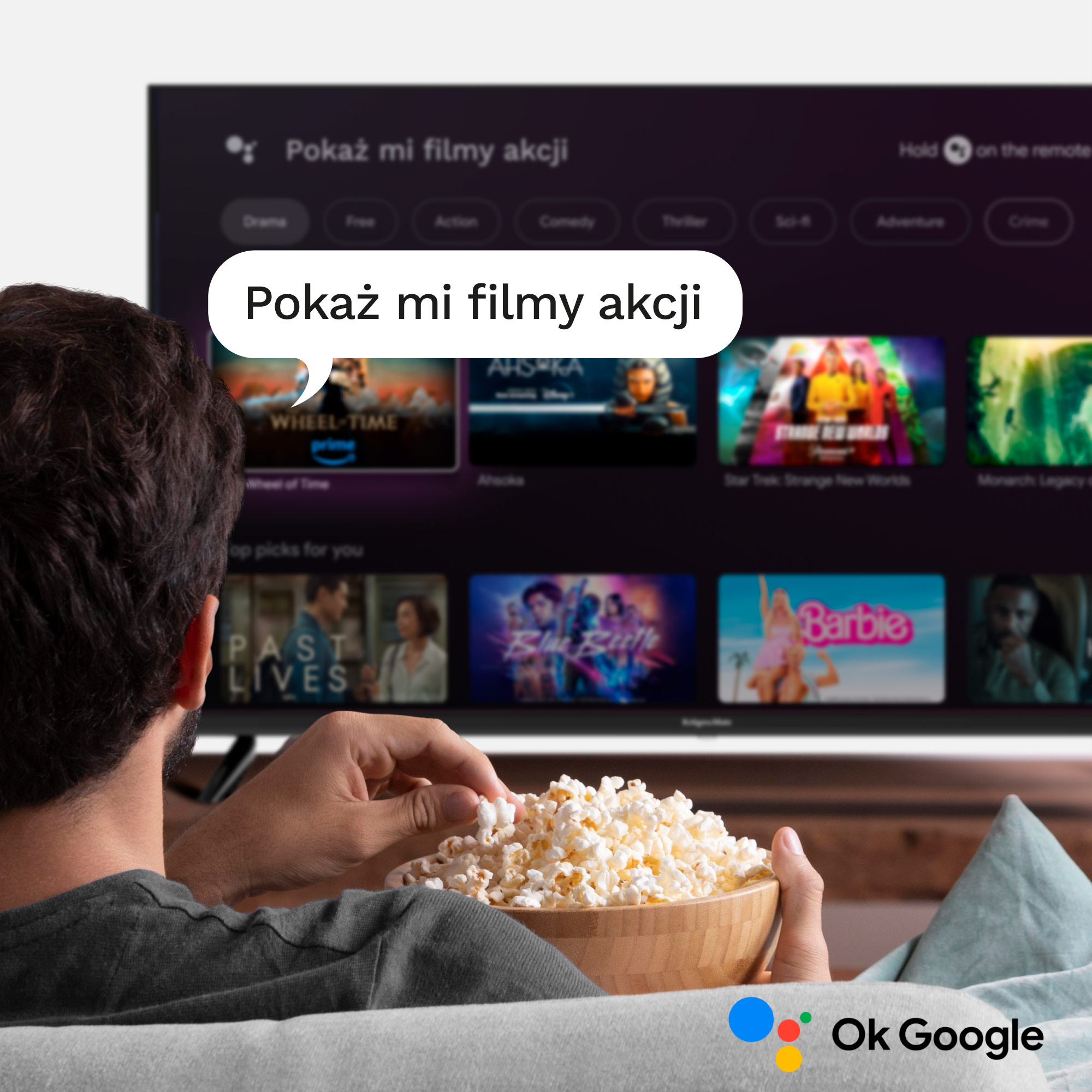 Mężczyzna je popcorn oglądając TV z propozycjami filmów i wyszukiwaniem głosowym.