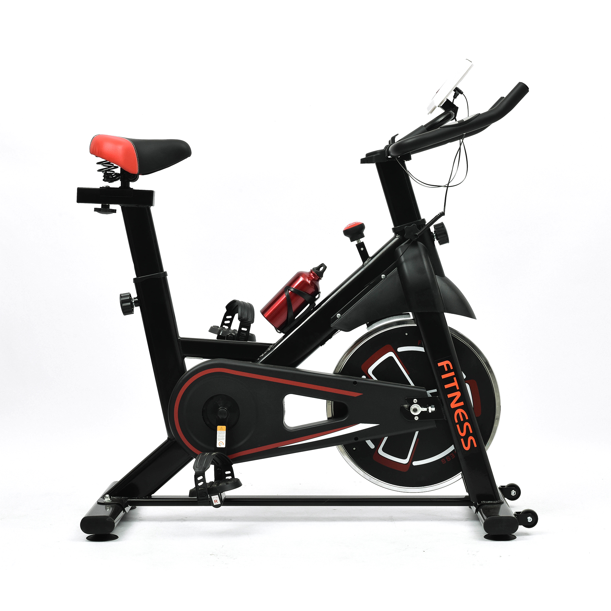 Una bicicleta estática negra con detalles rojos, botella de agua y soporte para tablet sobre fondo blanco.