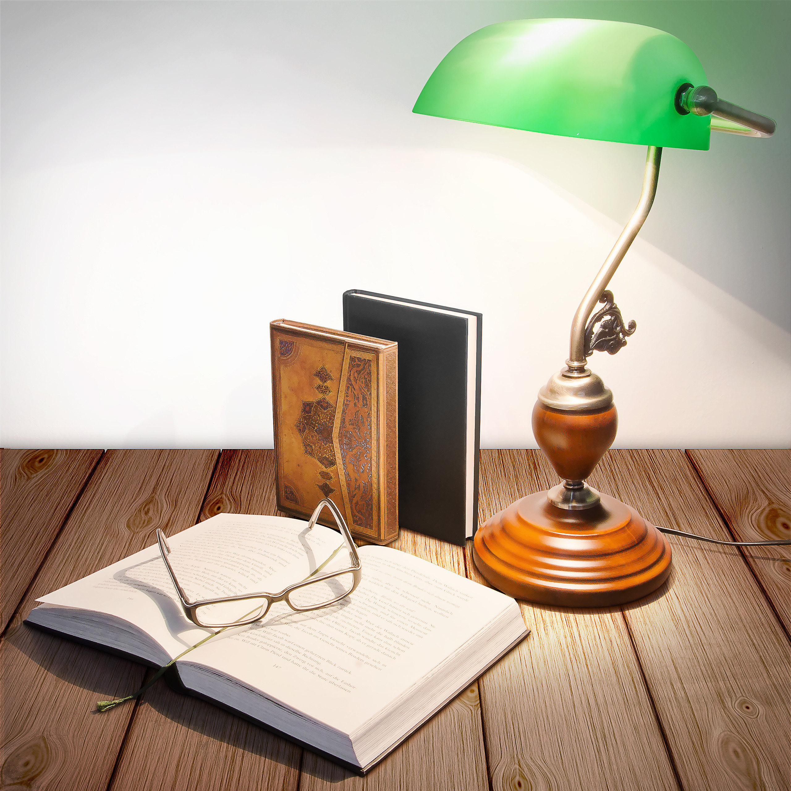 Eine grüne Lampe, Brille und aufgeschlagenes Buch auf Holz.