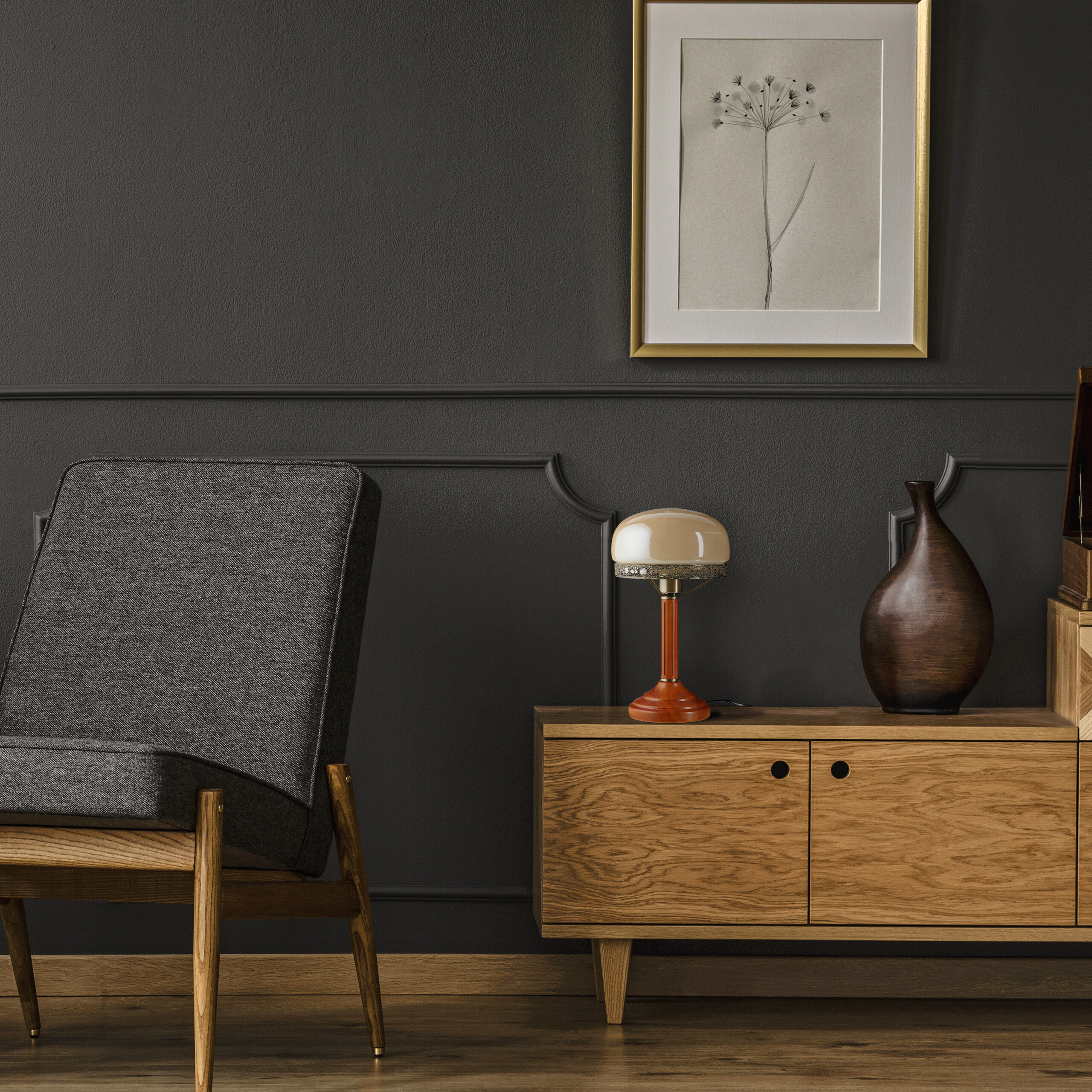Ein grauer Sessel, ein Holzkasten mit Lampe und Vase vor einer dunklen Wand mit gerahmtem Bild.