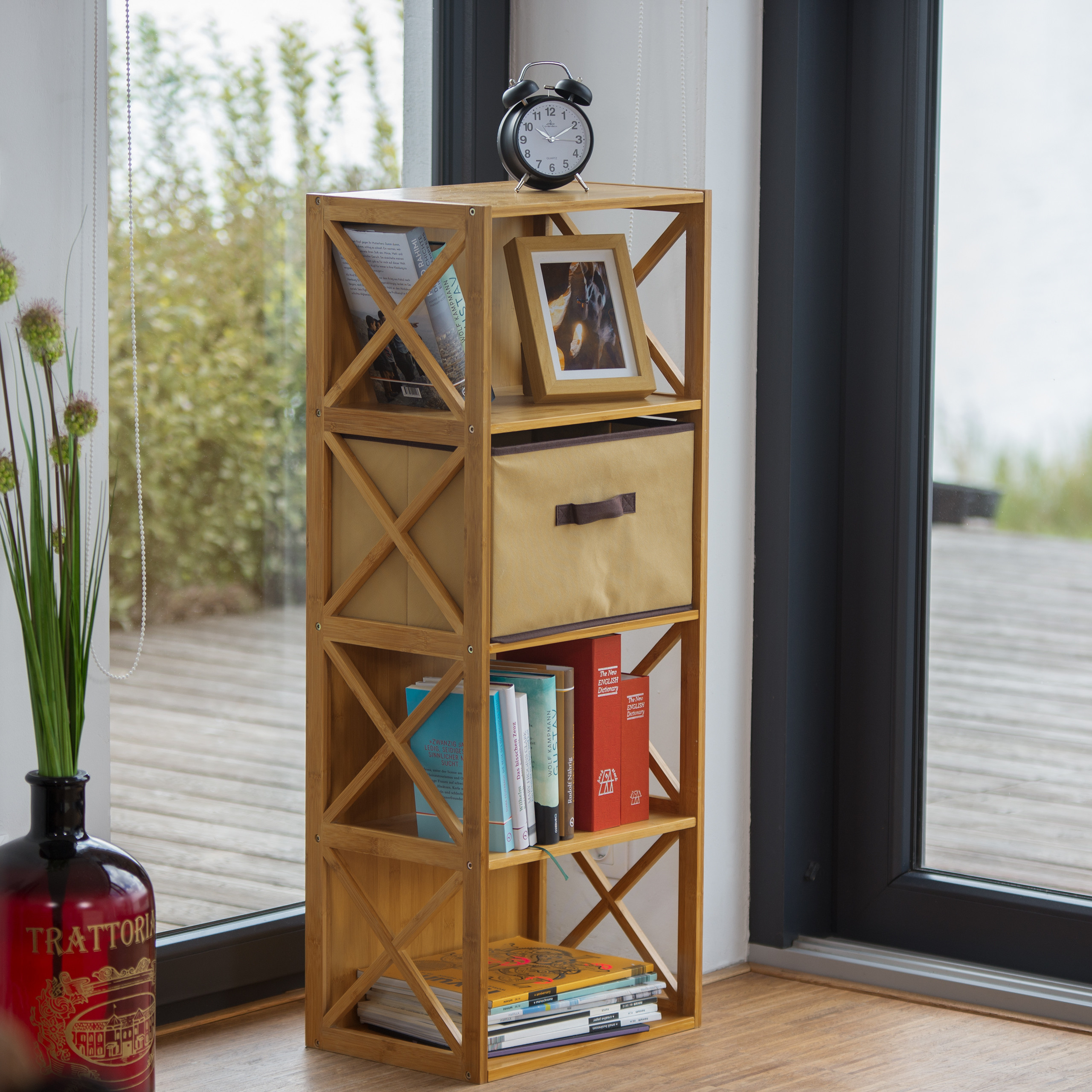 Ein hölzernes Regal mit Uhr, Bilderrahmen, Schublade, Büchern und Zeitschriften vor einem Fenster.