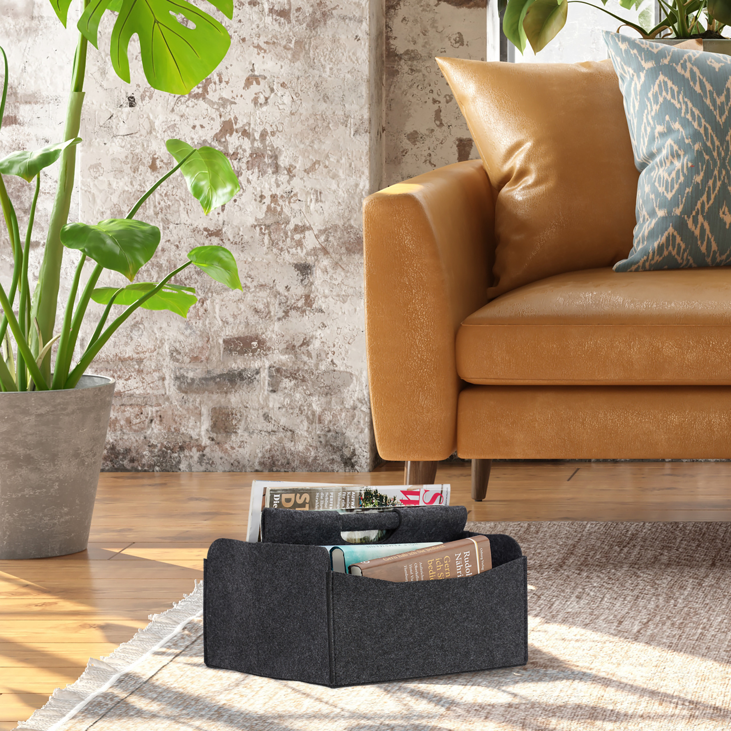 Ein grauer Filzkorb mit Zeitschriften steht auf einem Teppich neben einer Topfpflanze und einem gelben Sofa.