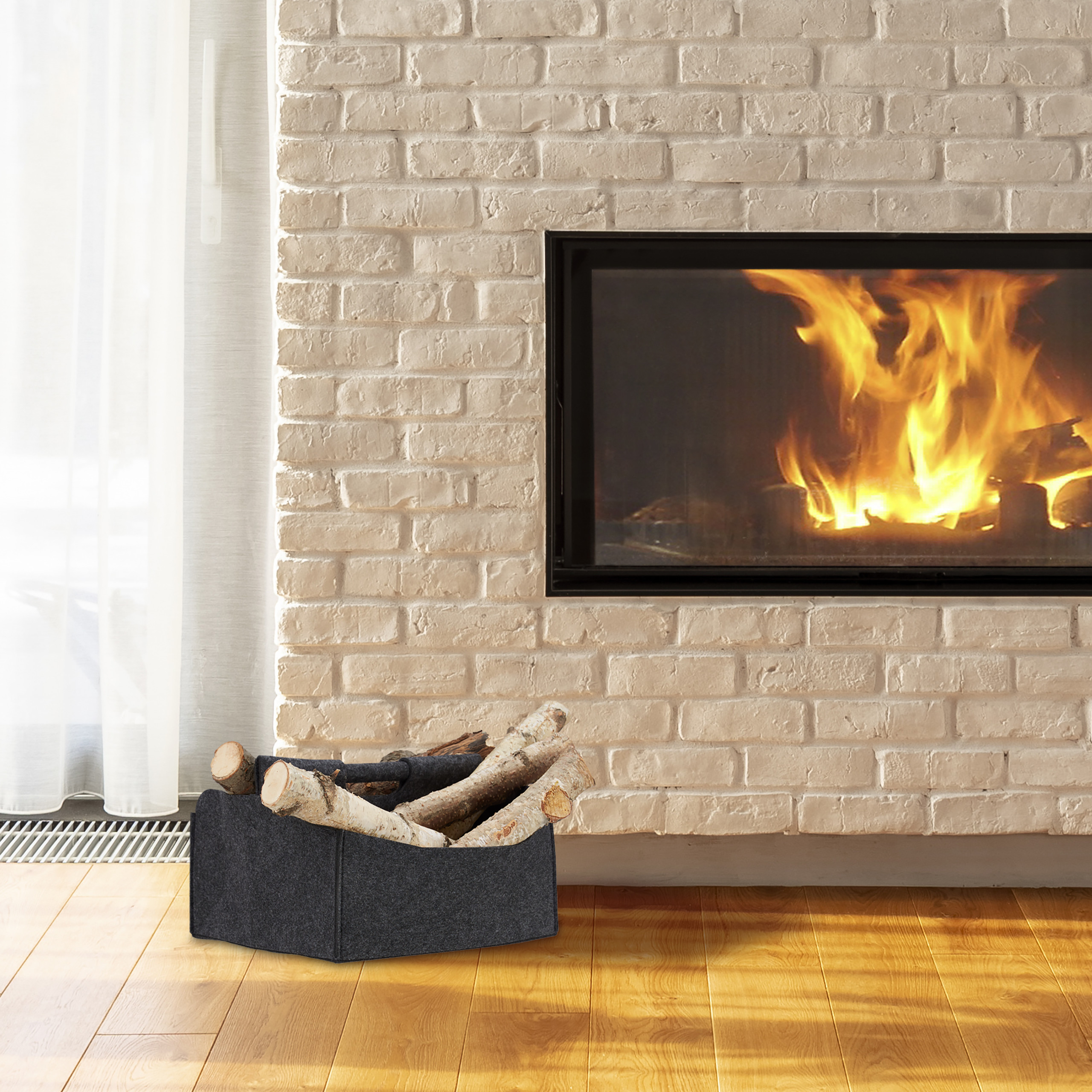 Ein Korb mit Brennholz steht auf Holzböden neben einem modernen Kamin mit brennenden Flammen.