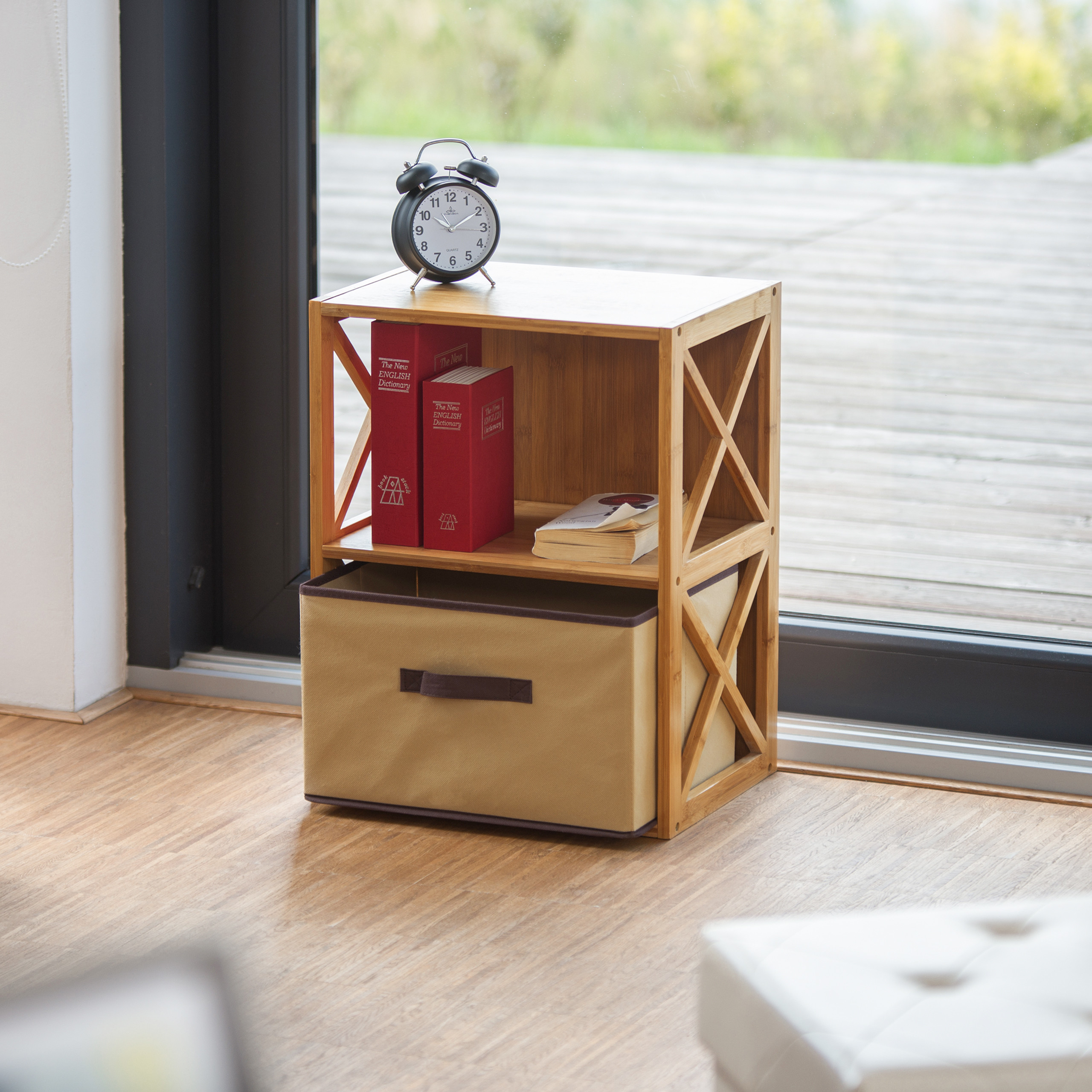 Ein hölzernes Regal mit rotem Buch, Uhr und beiger Box vor einer Glastür.