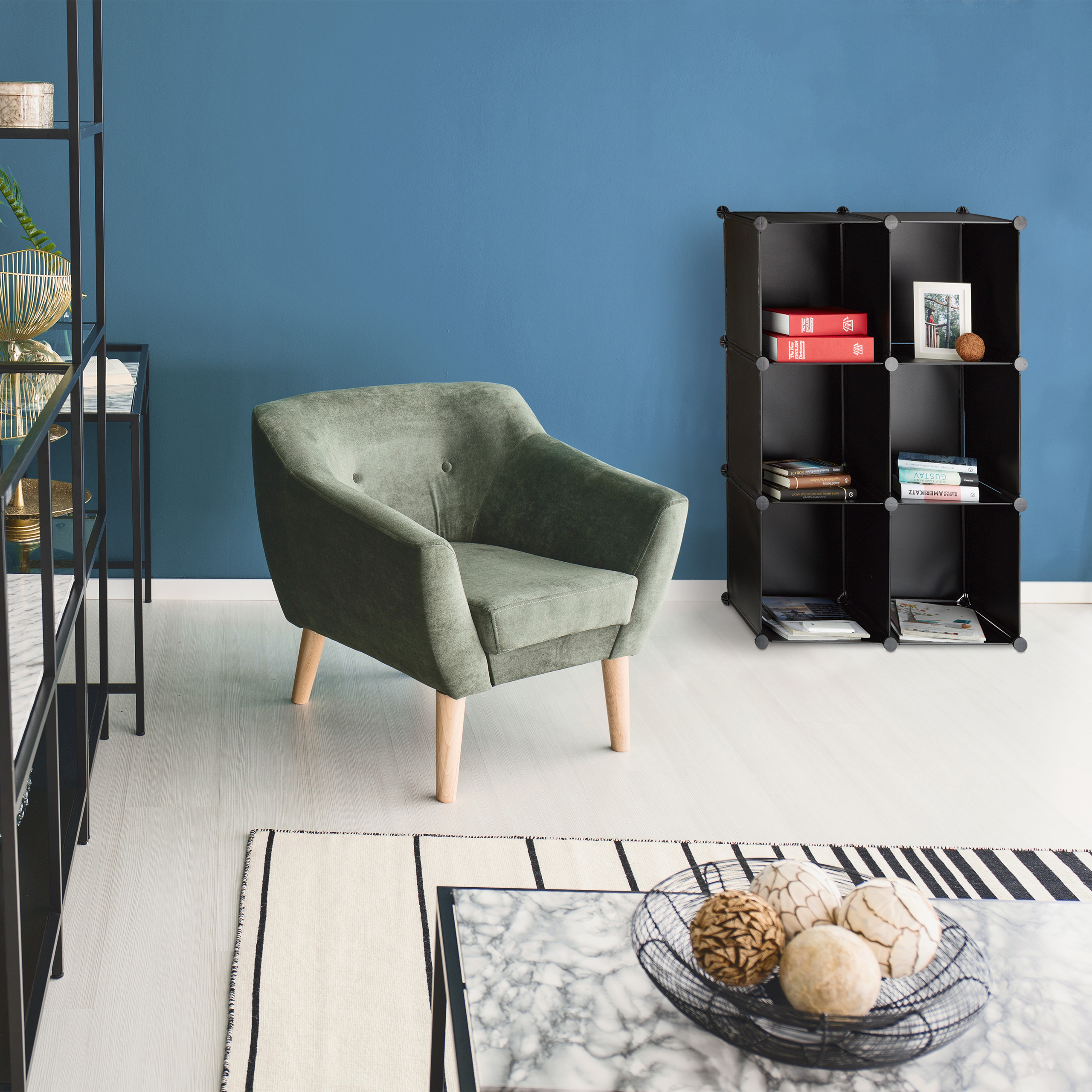 Grüner Sessel in Zimmer mit blauem Wand und schwarzen Regalen.