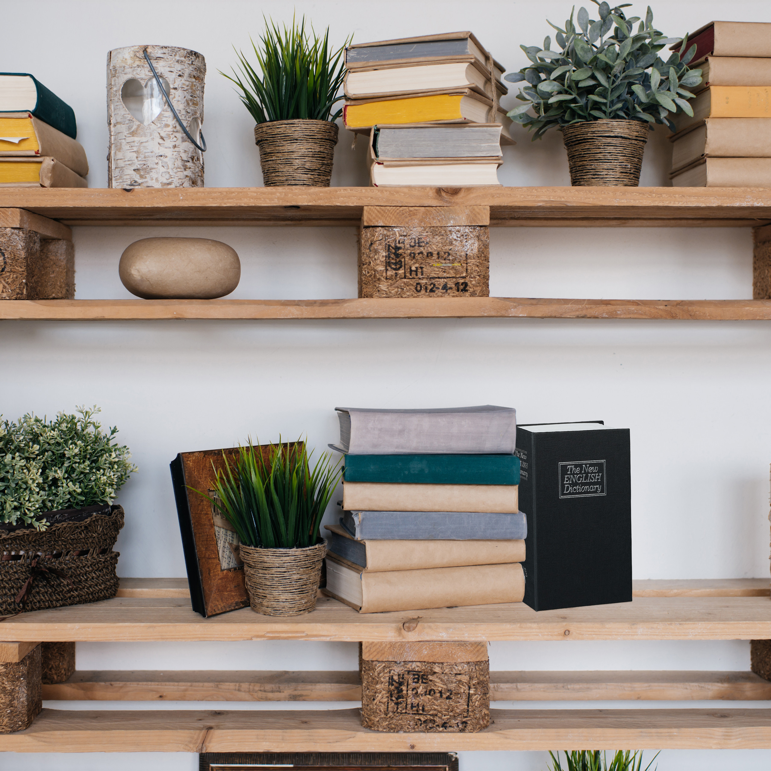 Holzregale voller Bücherstapel und kleiner Pflanzen in Töpfen an einer weißen Wand.