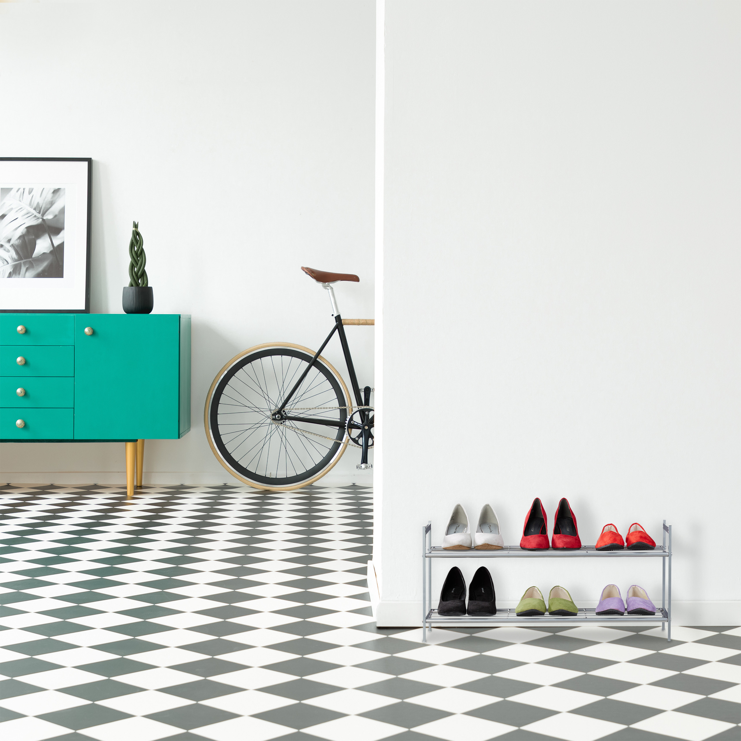 Flur mit schwarz-weißem Schachbrettboden, blauem Schrank, Fahrrad und einem zweistöckigen Schuhregal.