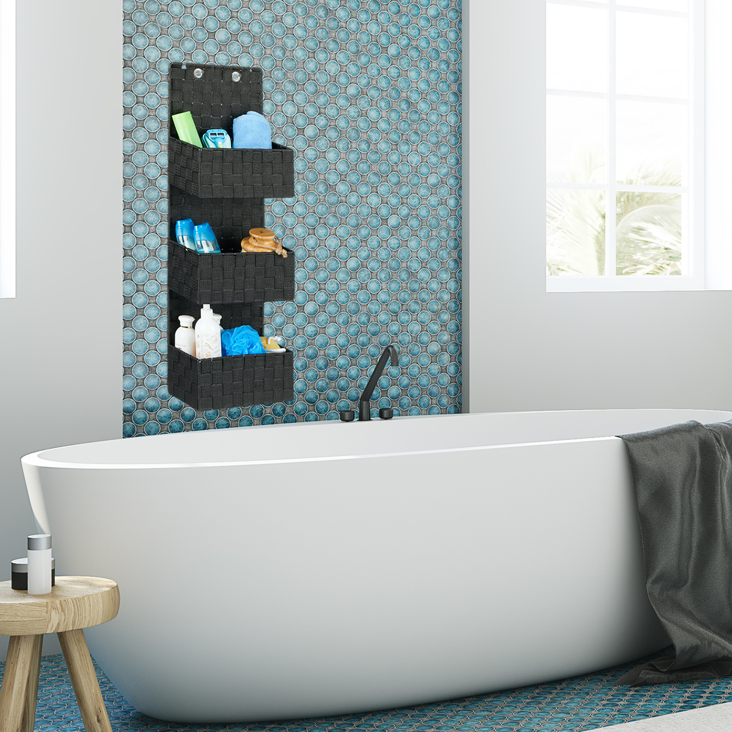 Weiße Badewanne mit Hängetasche für Kosmetika an einer blau gefliesten Wand mit Fenster.