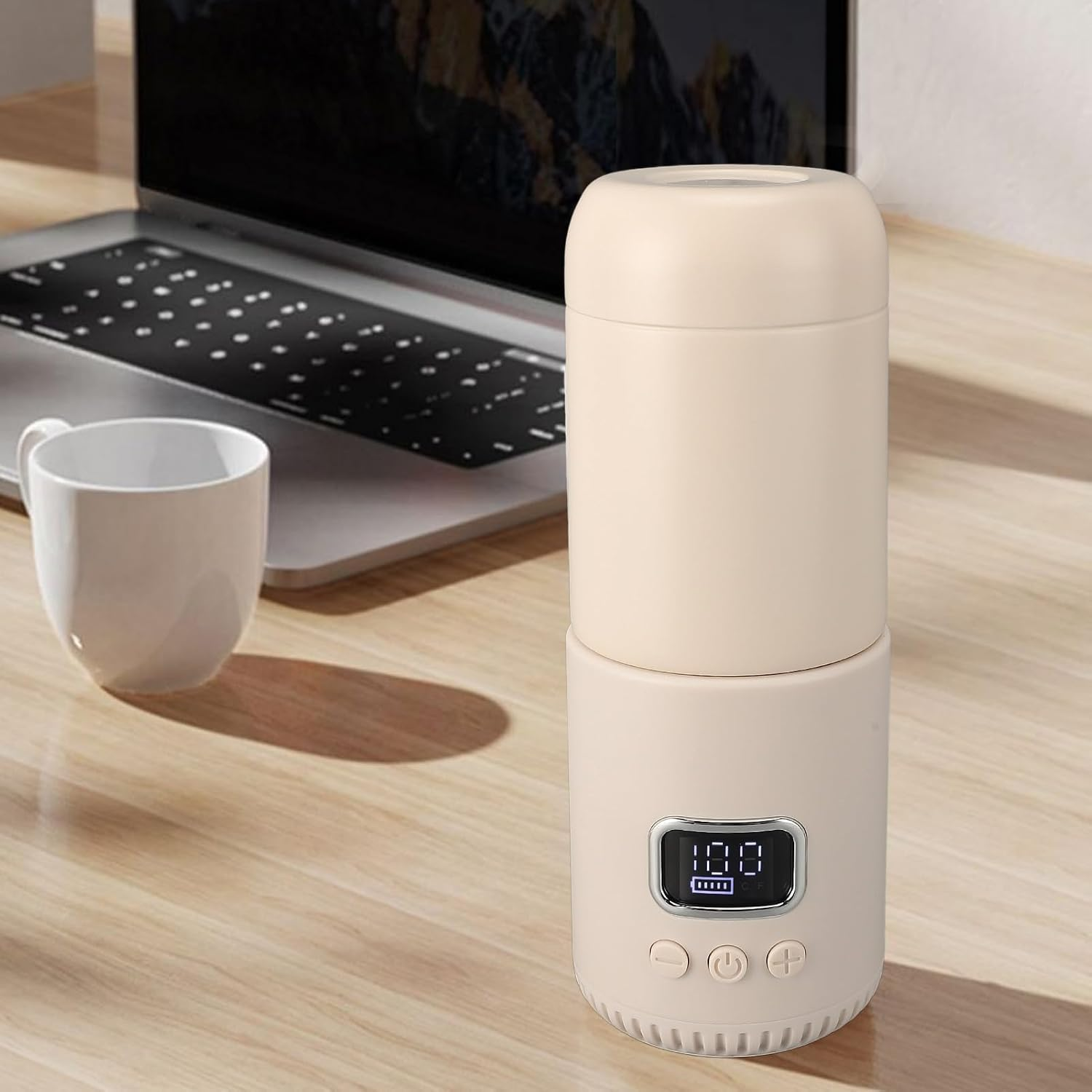 Ein beiger Diffusor mit Digitalanzeige steht auf einem Holztisch neben Laptop und Tasse.