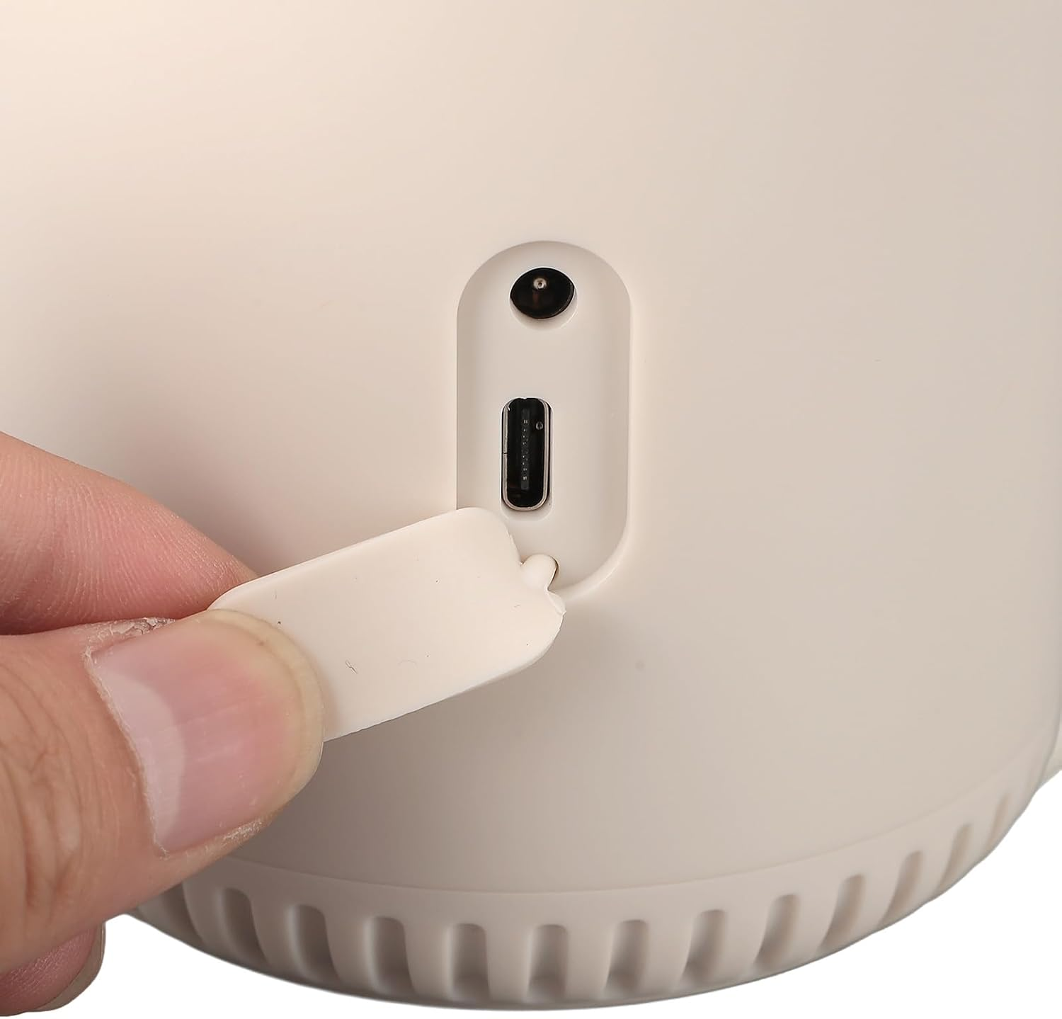 Eine Hand öffnet eine Schutzklappe an einem weißen Gerät und gibt einen USB-C-Anschluss frei.