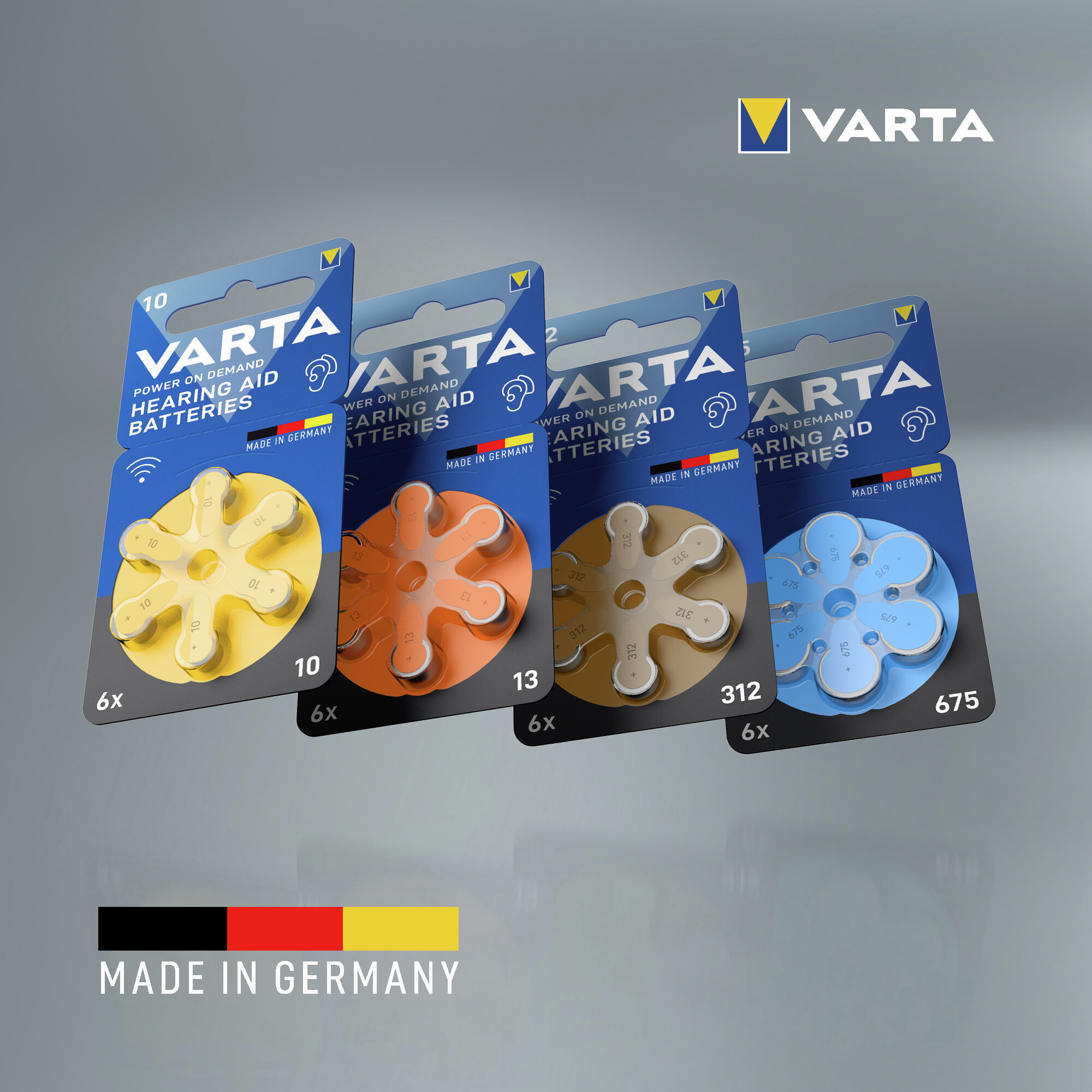 Vier Varta Hörgerätebatteriepackungen in Gelb, Orange, Braun und Blau vor grauem Hintergrund mit der Aufschrift Made in Germany.