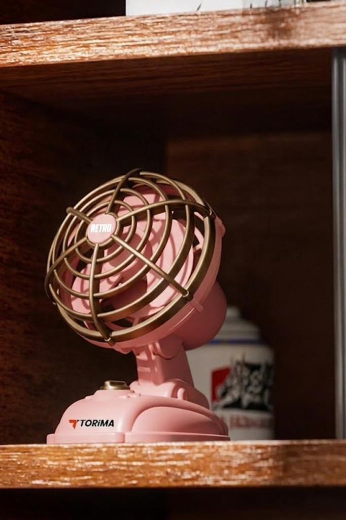 Bronz renkli kafese sahip pembe retro Torima masa vantilatörü ahşap rafta duruyor.