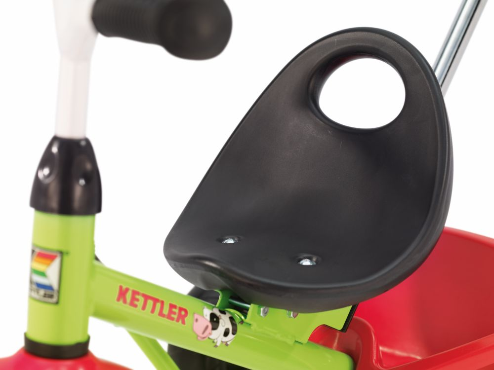 Nahaufnahme eines grünen und roten Dreirads für Kinder mit schwarzem Kunststoffsitz.