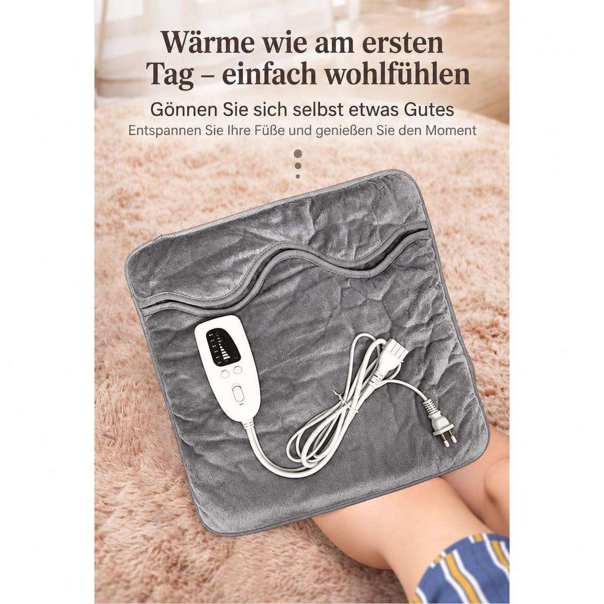 Graues elektrisches Fußwärmkissen auf flauschigem Teppich mit weißer Fernbedienung und Kabel.