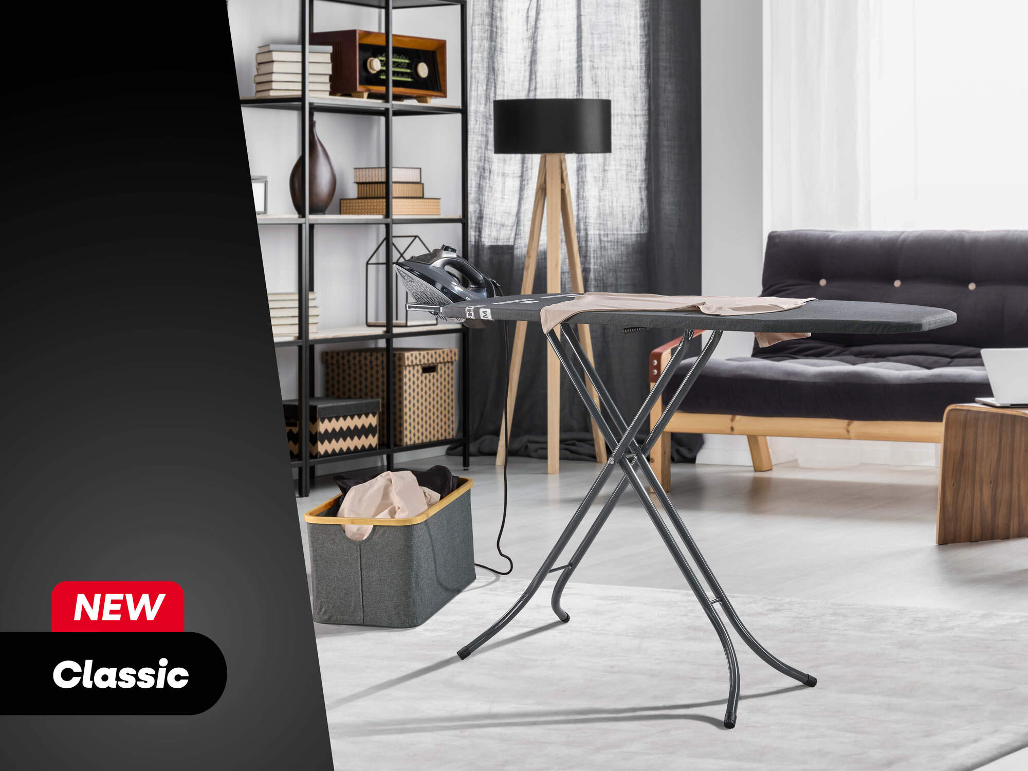 Ein graues Bügelbrett mit einem Bügeleisen steht in einem hellen Wohnzimmer mit Regal und Sofa.