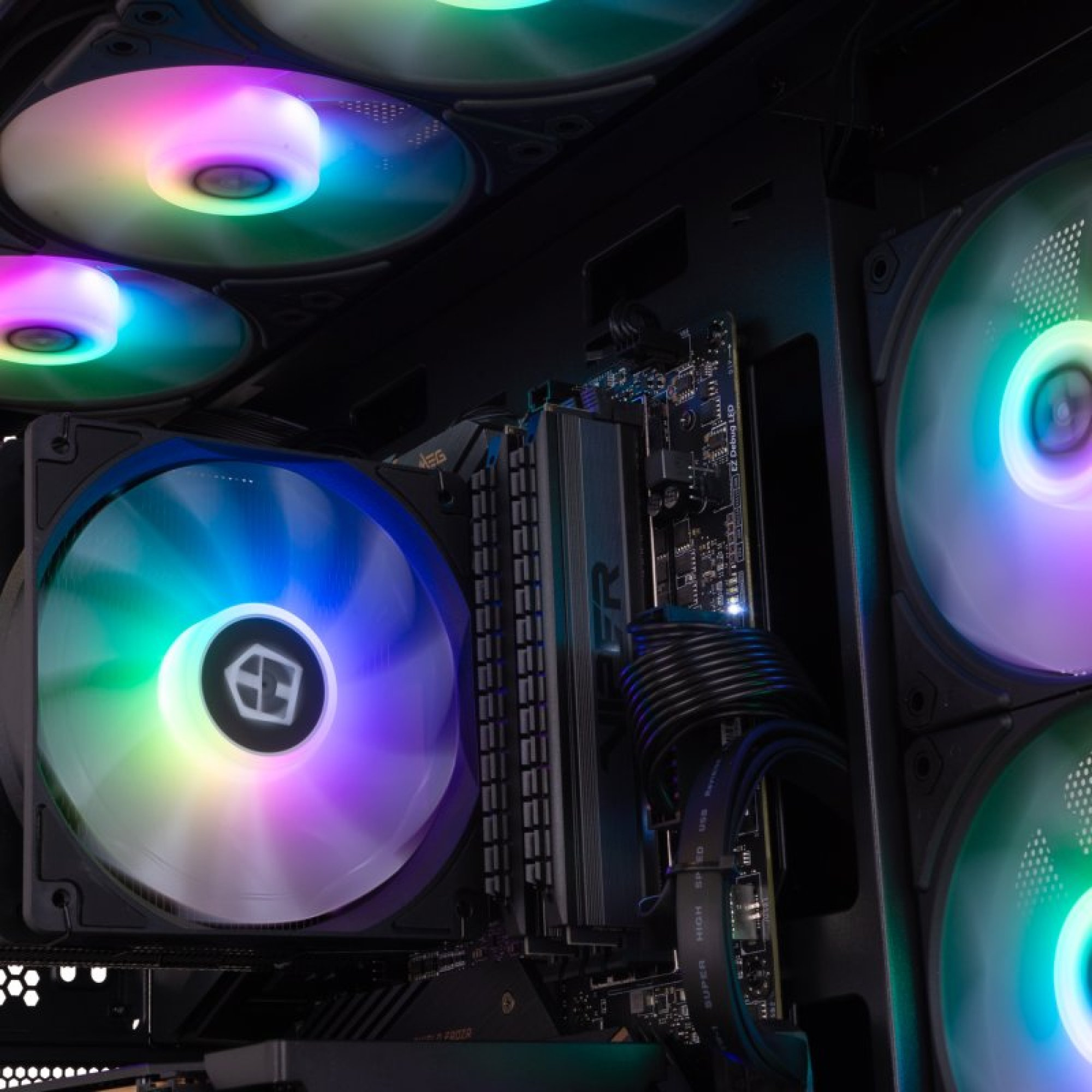 Vista interior de una PC gamer con ventiladores RGB vibrantes, placa base y componentes oscuros.