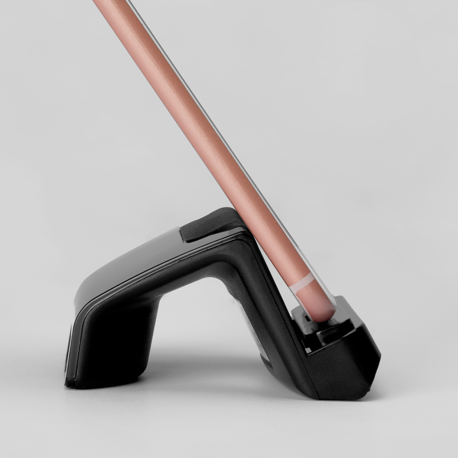 Un teléfono inteligente rosa descansa sobre un soporte negro sobre un fondo claro.