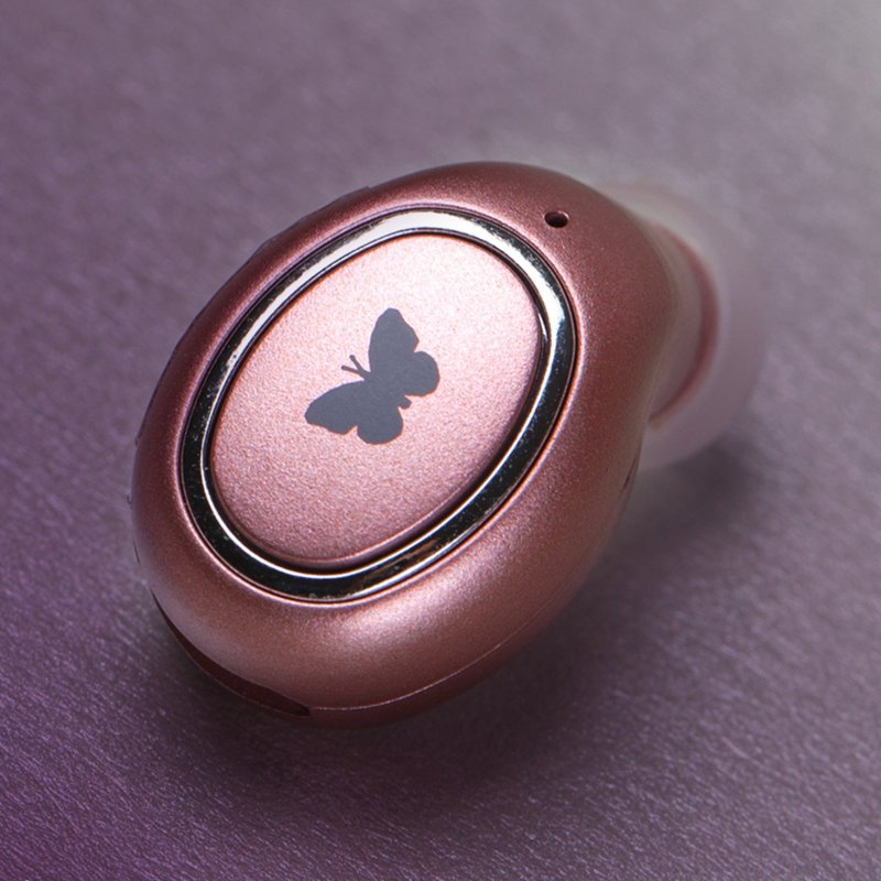 Un auricolare wireless oro rosa con un'icona a farfalla nera su una superficie viola.