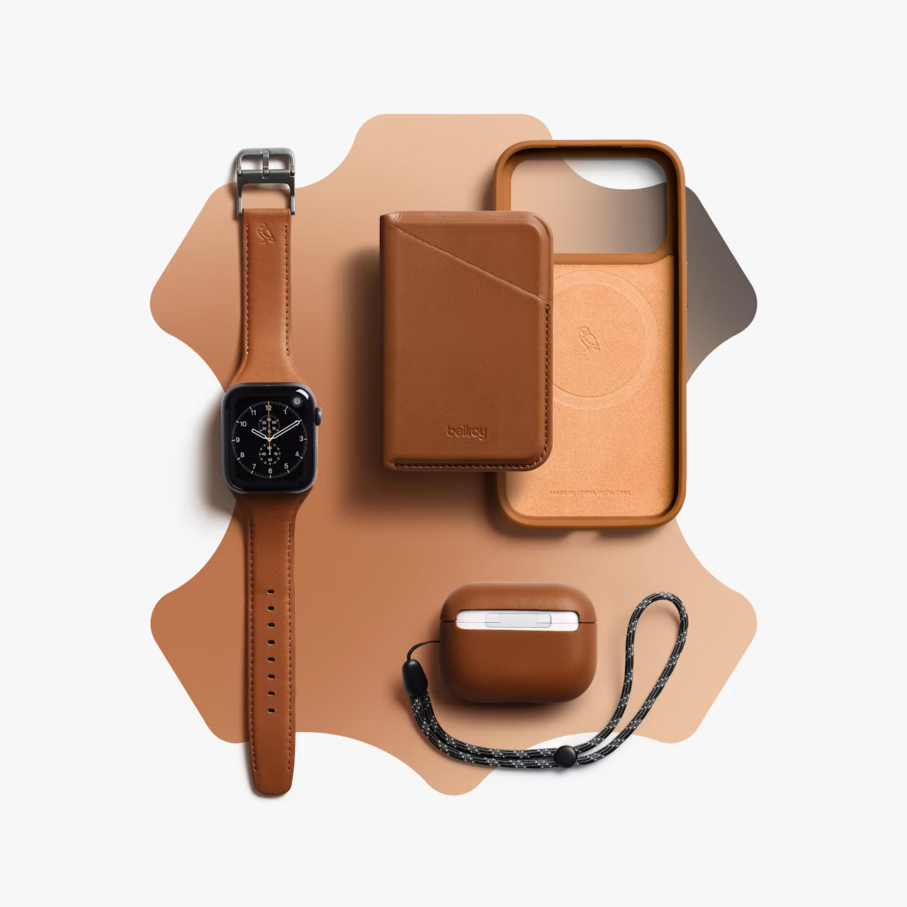 Brązowe skórzane akcesoria technologiczne: smartwatch, portfel, etui na telefon i AirPods.