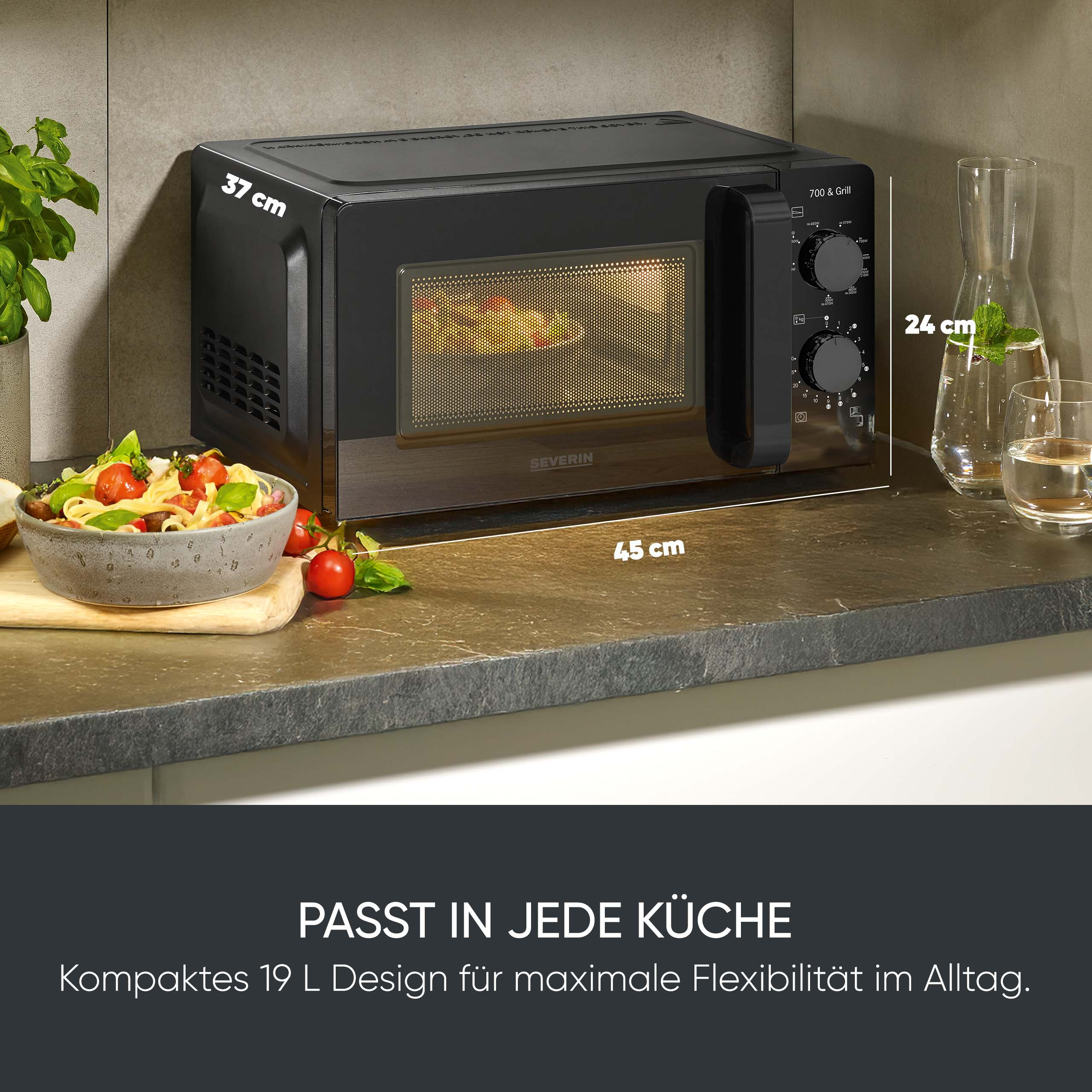 Eine schwarze Mikrowelle steht auf einer Küchentheke mit Pasta und einer Karaffe Wasser.
