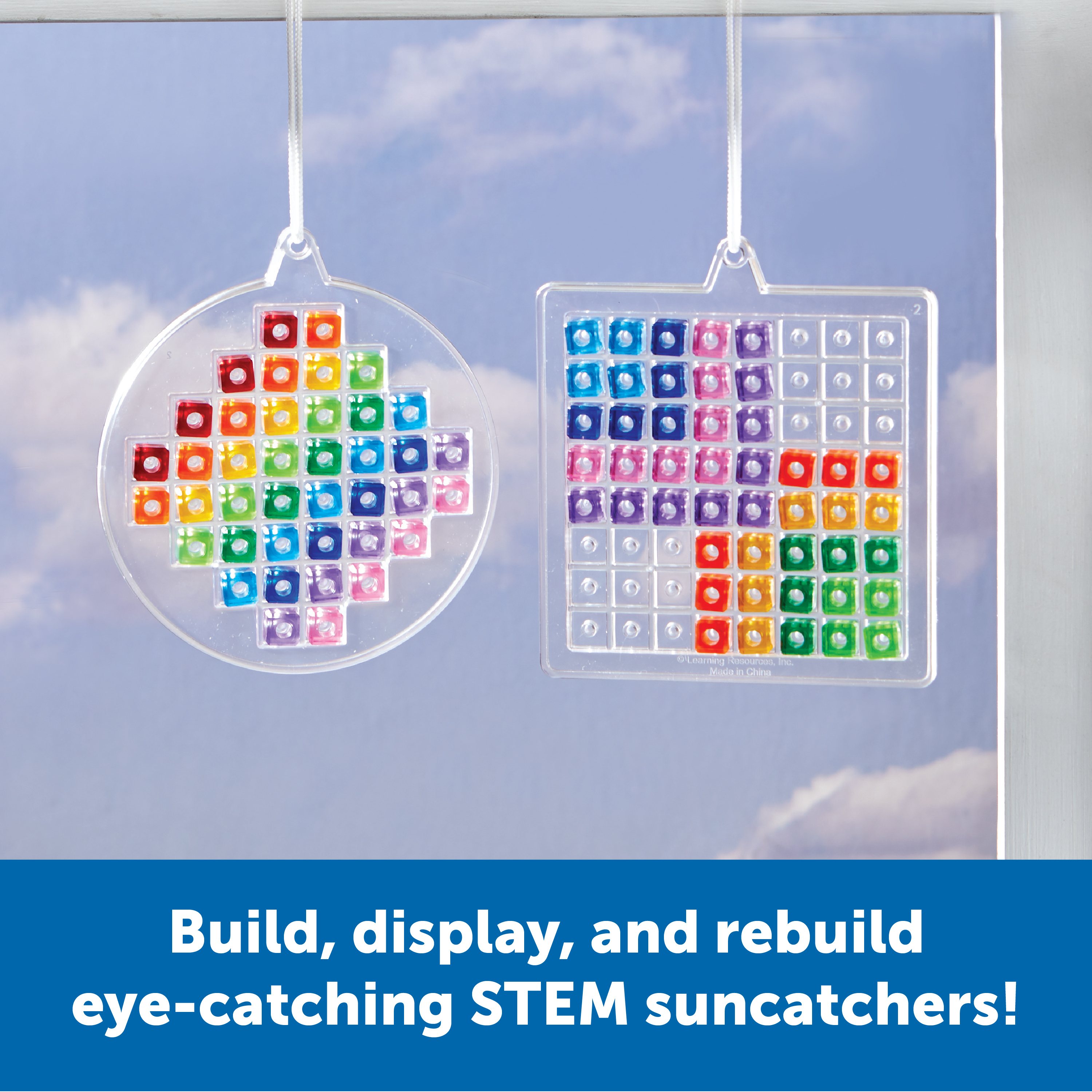 Zwei hängende Acryl-Suncatcher mit bunten Glassteinen gegen blauen Himmel.