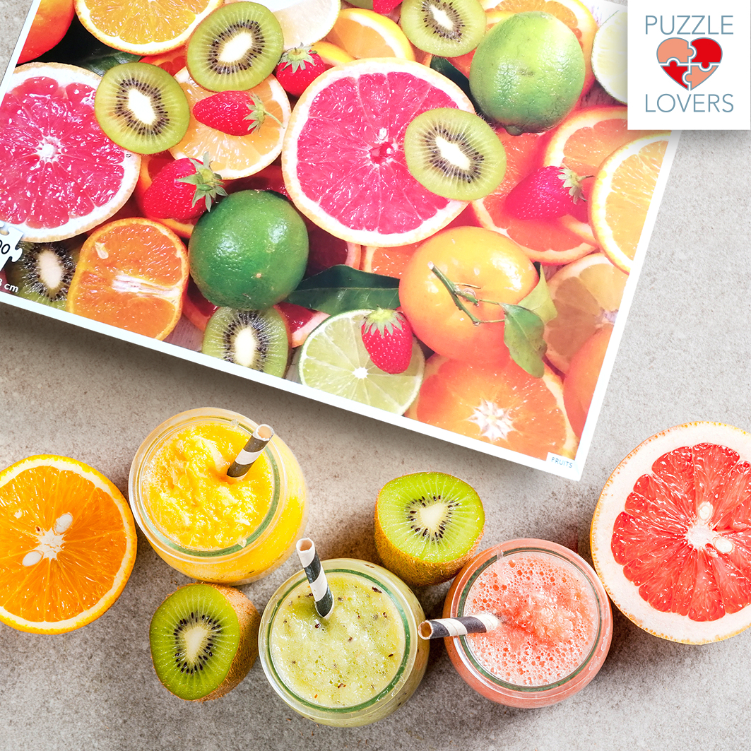 Batidos de frutas en tarros rodeados de pomelos, naranjas, kiwis y fresas cortados.