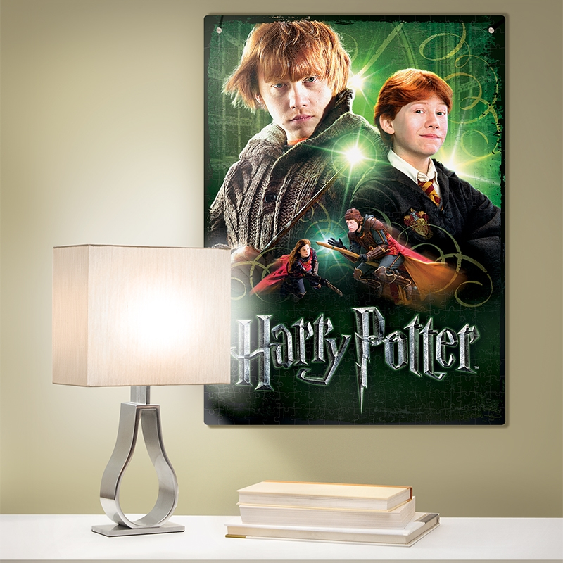 Cartel de Harry Potter en la pared, una lámpara y libros en la mesa blanca delante.