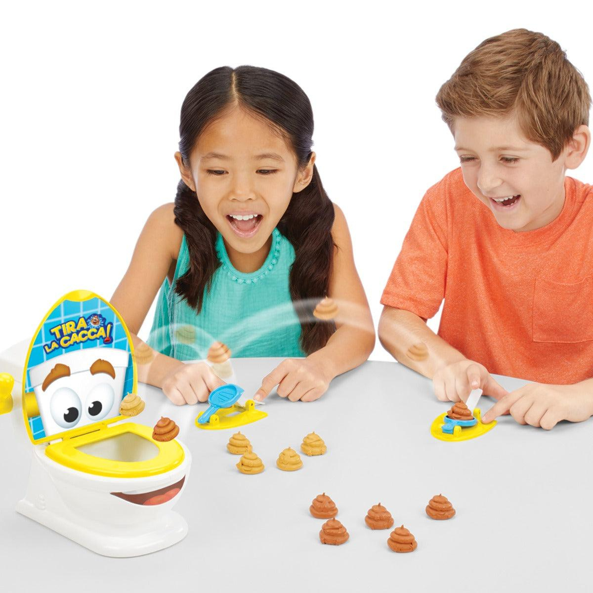 Zwei Kinder spielen begeistert ein Toiletten-Spiel und schleudern kleine Plastik-Kackhaufen in eine lächelnde Spielzeugtoilette.