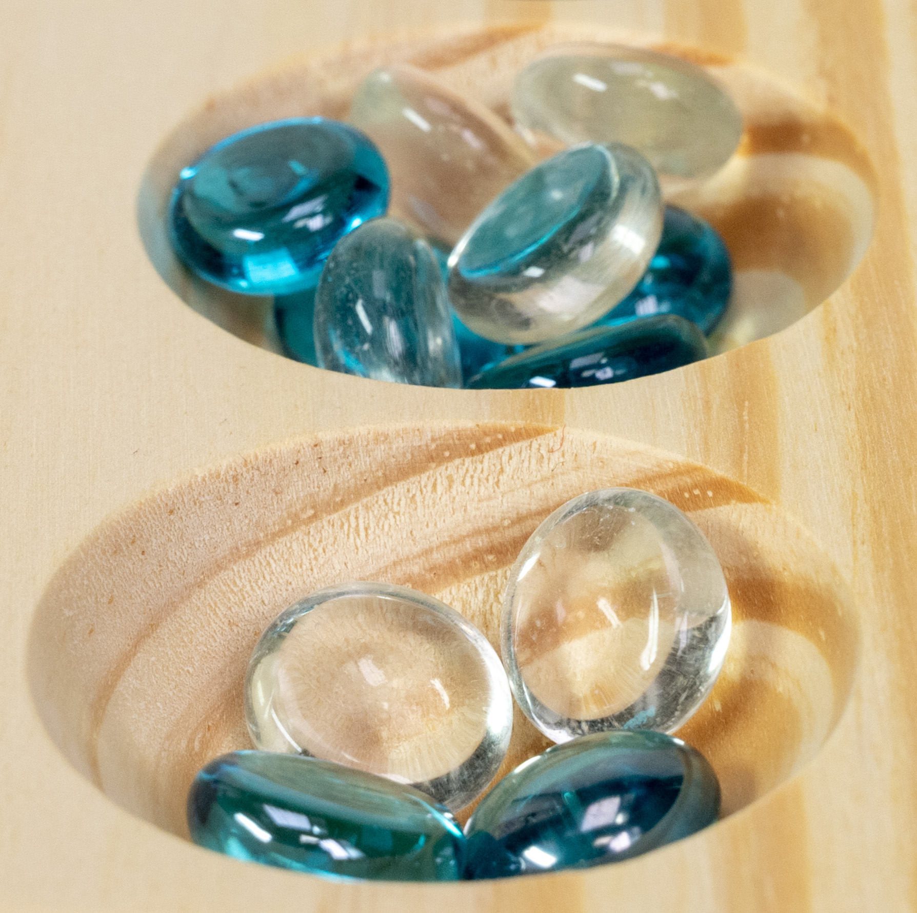 Blau und transparente Glasmurmeln in Holzmusein auf einem Brett.