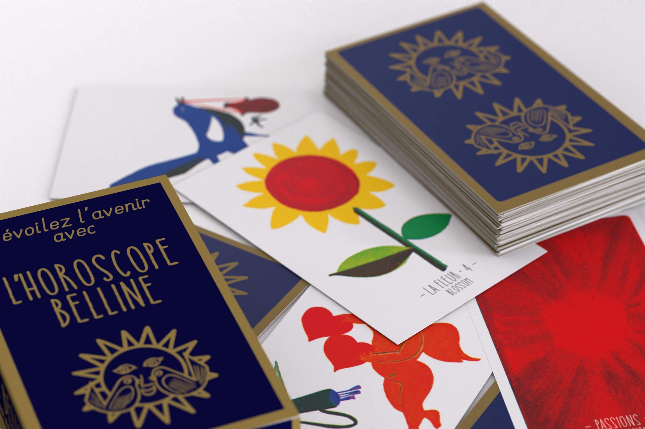 Ein blaues Kartenspiel namens L'Horoscope Belline mit bunten Karten, darunter eine Sonnenblume und rote Figuren.