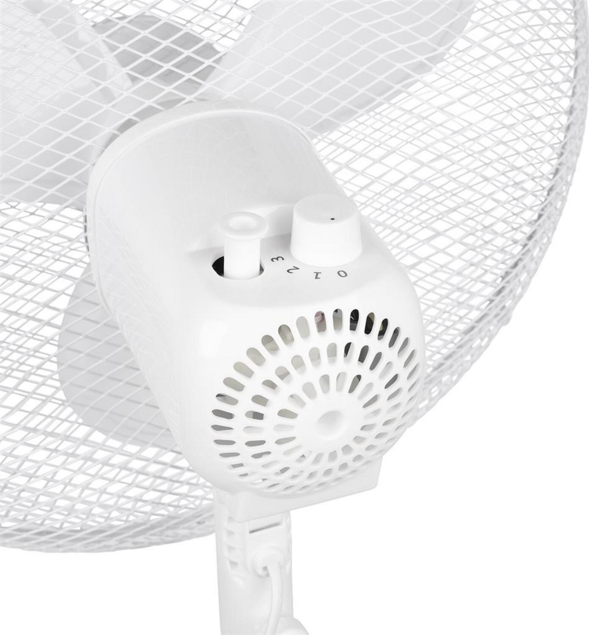 Primer plano de los botones de control y la carcasa del motor de un ventilador de pie blanco.