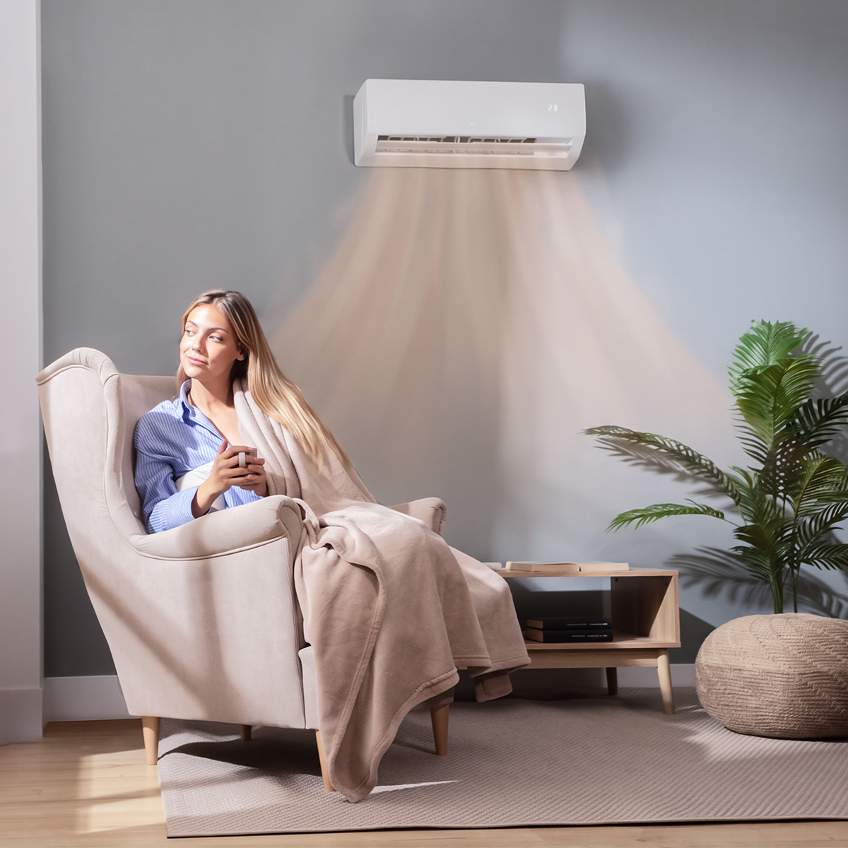 Una mujer se relaja en un sillón bajo el flujo de aire cálido de un aire acondicionado.