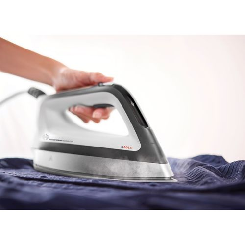 Una mano sostiene una plancha de vapor blanca y negra mientras emite vapor sobre ropa azul.