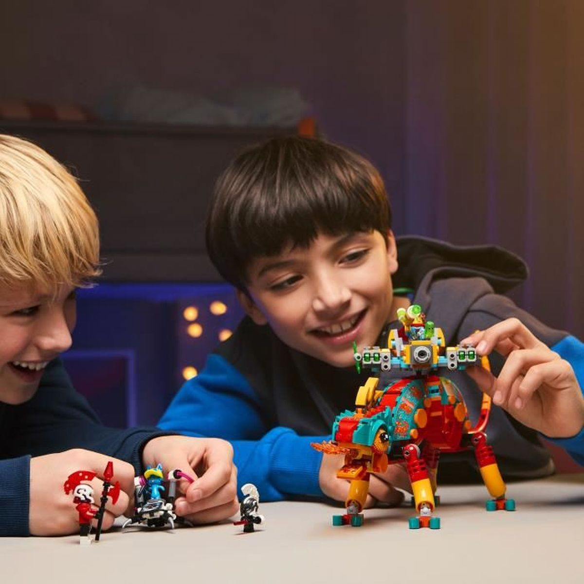 Dos niños sonrientes jugando con coloridos juguetes de Lego en una mesa.