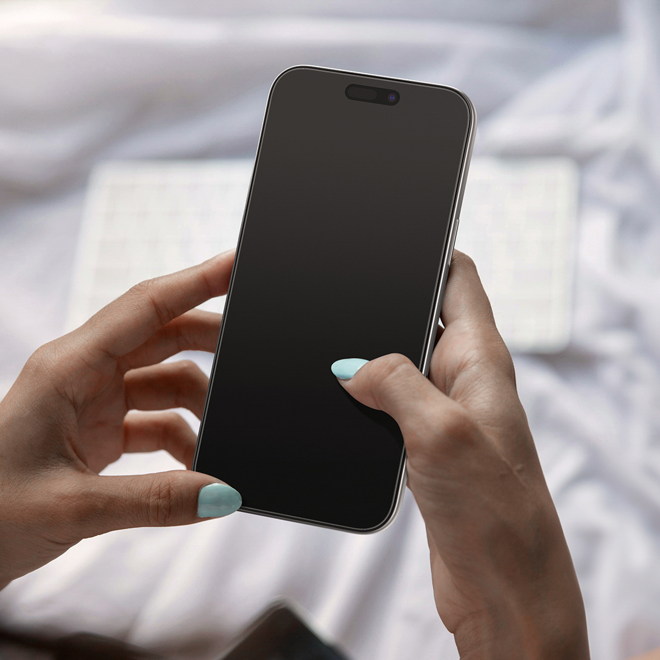 Osoba trzymająca czarny smartfon z jasnoniebieskim lakierem na białym tle.