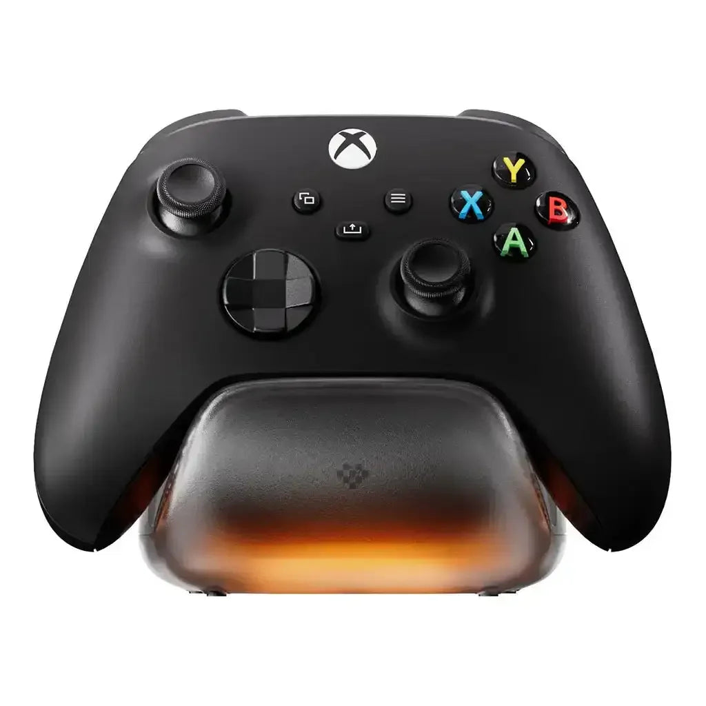 Czarny kontroler Xbox spoczywa na stacji ładującej z pomarańczową podstawą.