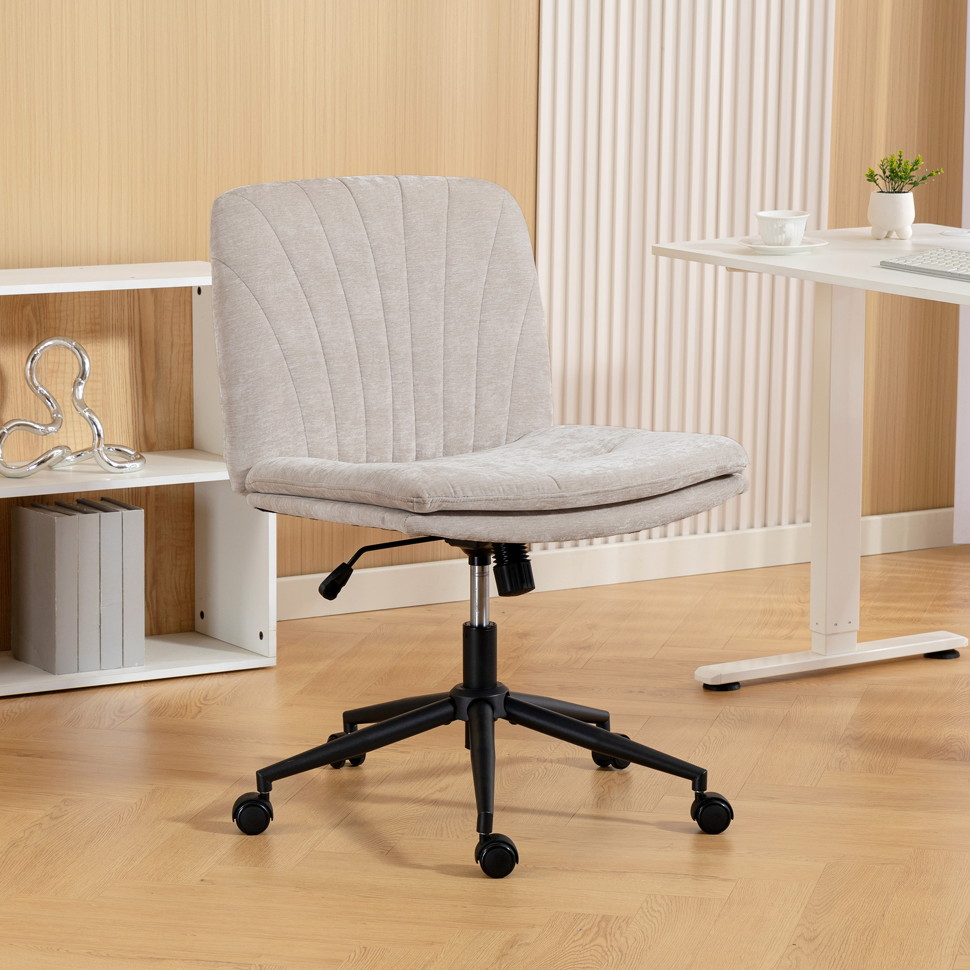 Una sedia da ufficio imbottita beige con ruote nere si trova in una stanza con una scrivania bianca e pareti in legno.
